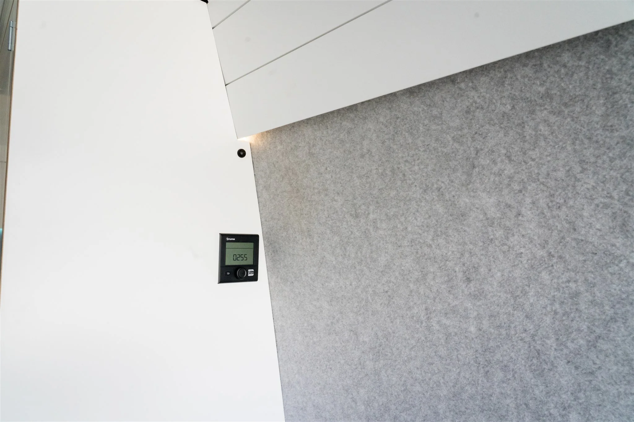 Modern office interior with white wall, gray carpeted floor, and a digital display showing the number 0255.
