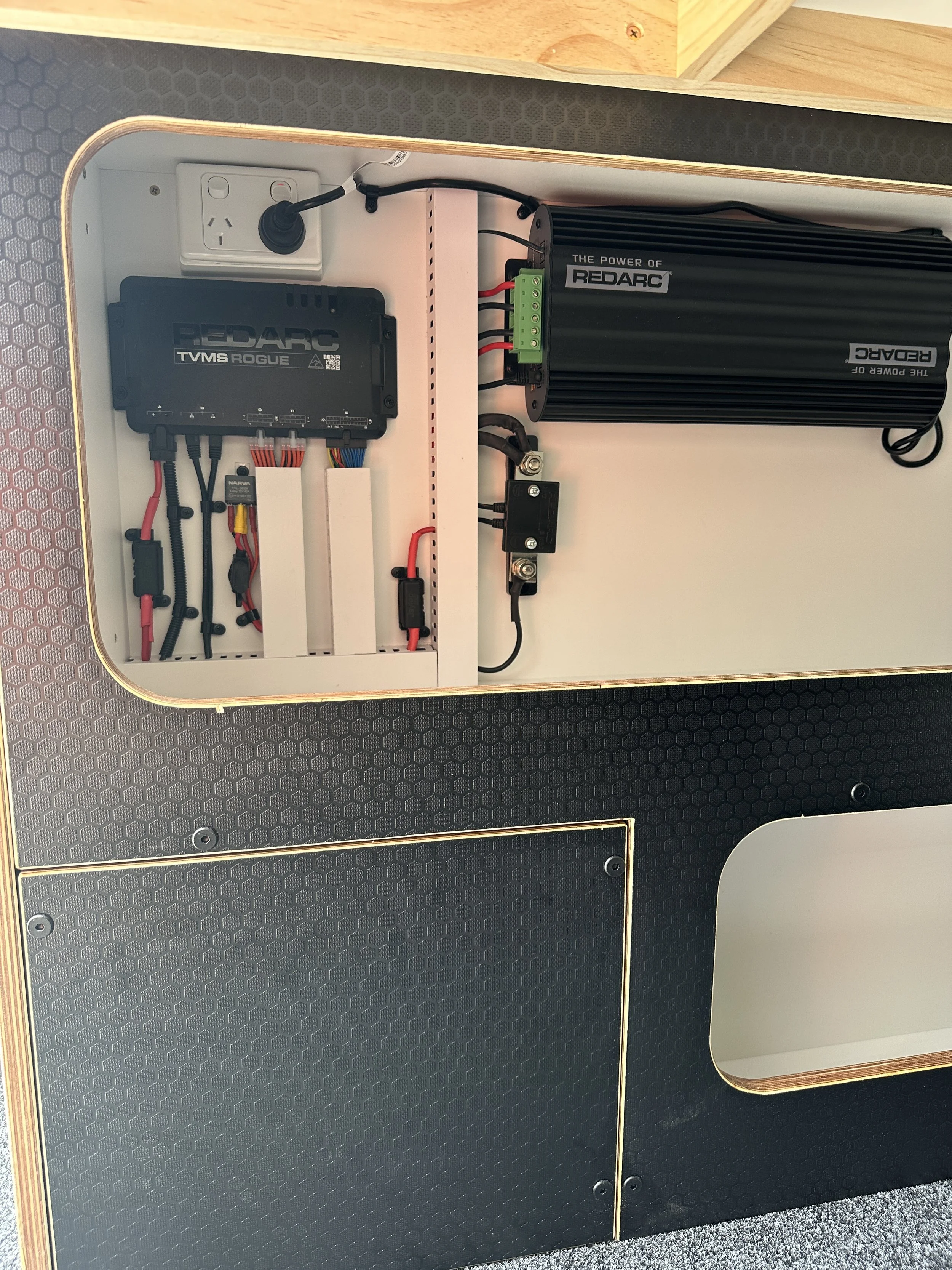 Close-up view of an electronic control panel inside a cabinet, featuring a pedal controller, a power inverter, and wiring.