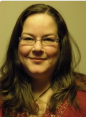 A woman with glasses and long brown hair smiling at the camera.