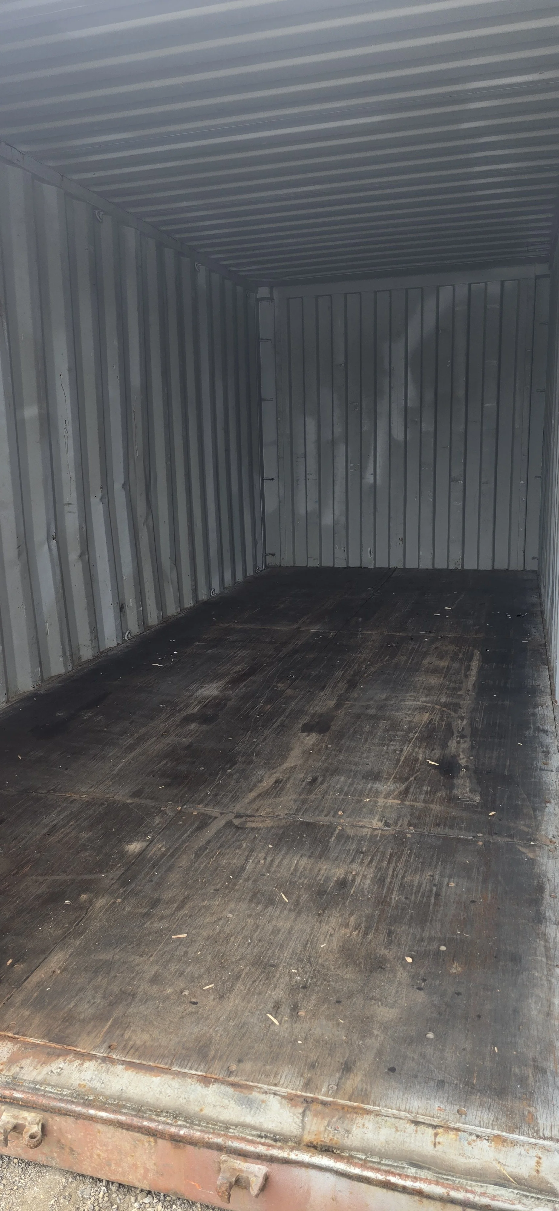 Interior of used 20ft shipping container with one door open showing wooden floor
