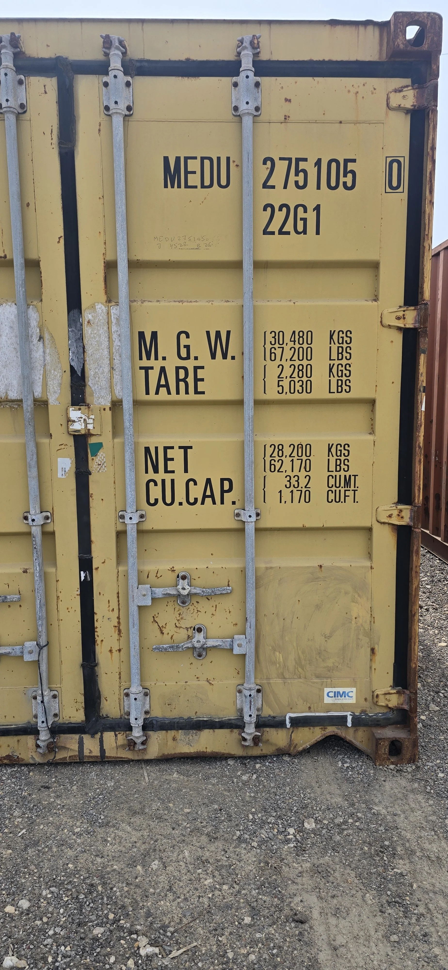 Close-up of right door on yellow 20ft shipping container showing locking bars and hinges