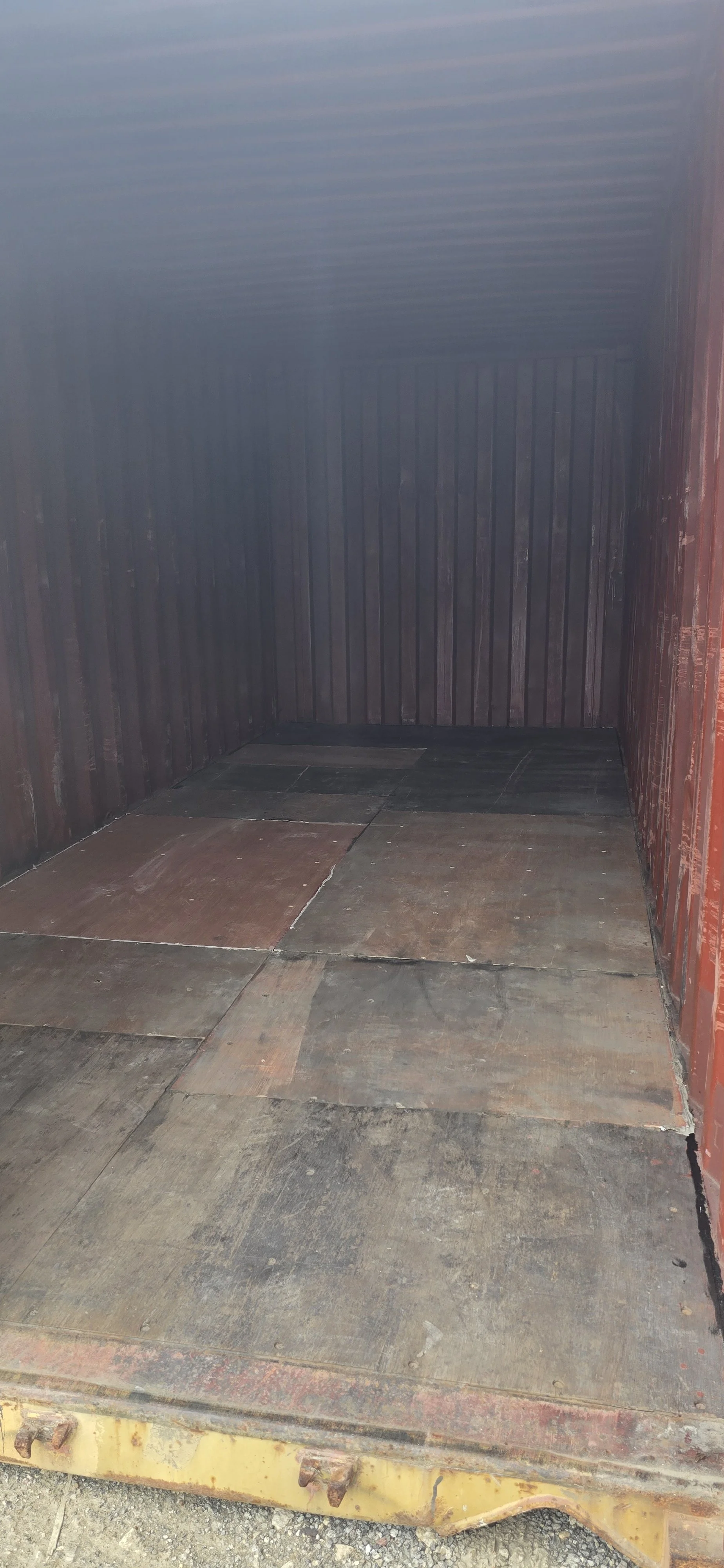 Interior of yellow used 20ft shipping container with one door open and wooden floor