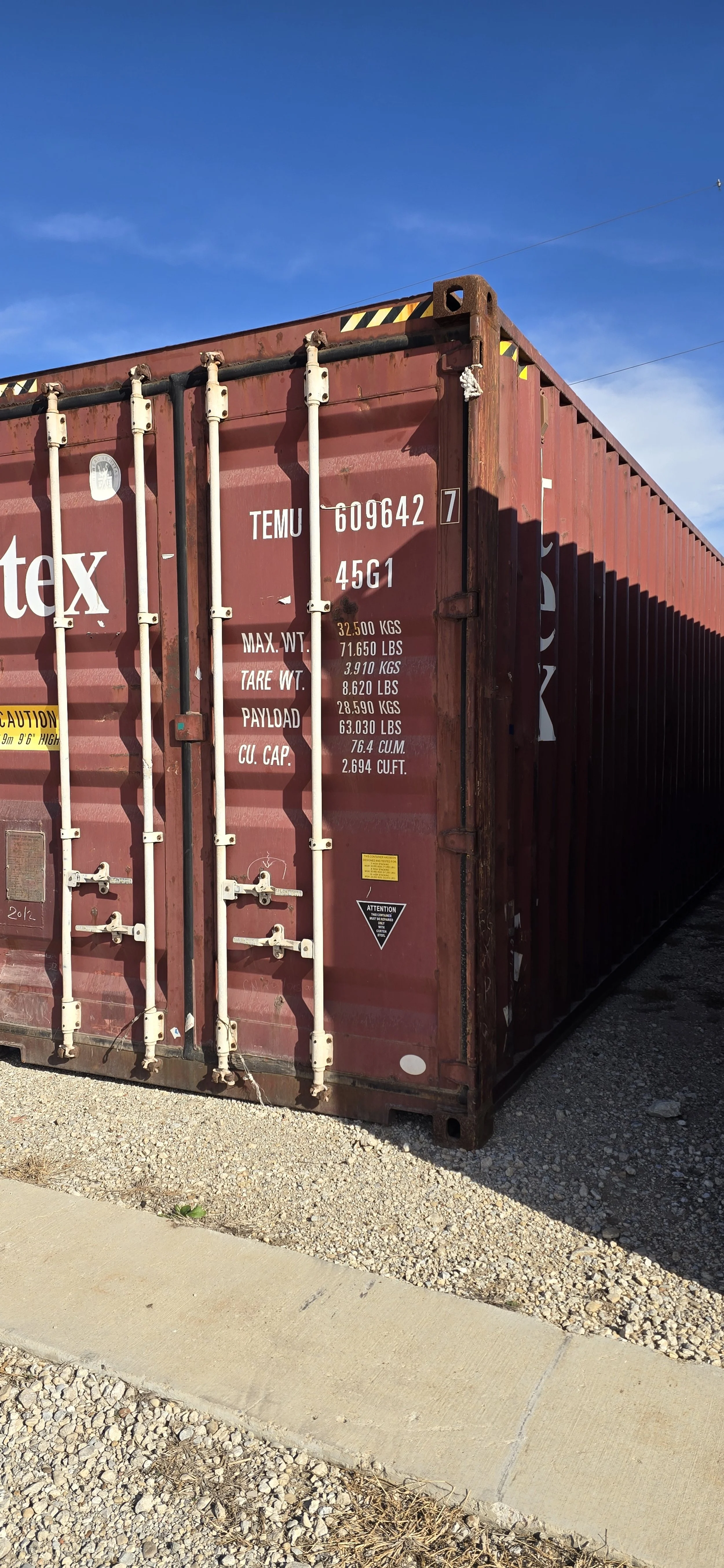 Side angle exterior view of a used 40 ft shipping container in Fort Worth, TX showing corrugated steel walls and wind and water tight condition.