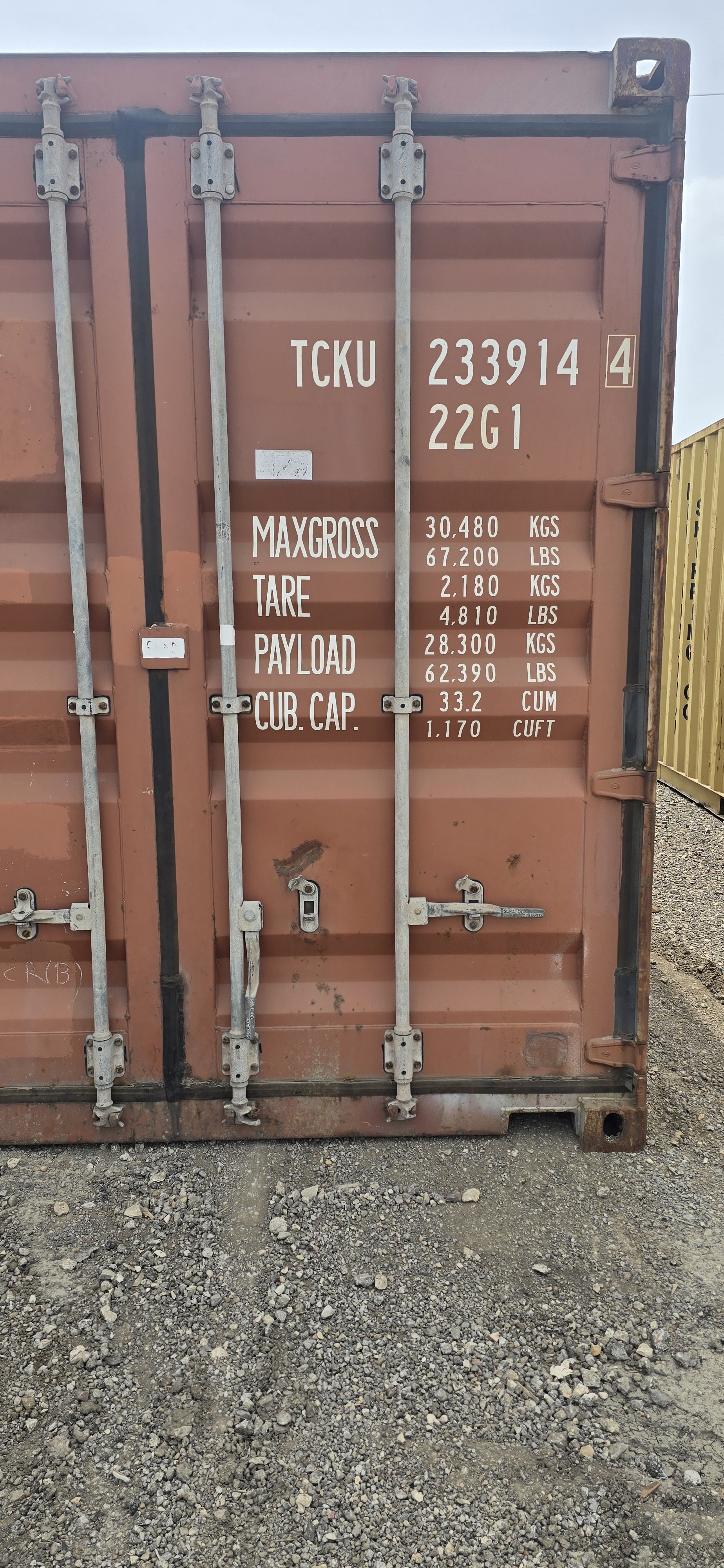 Close-up of right door on brownish red used 20ft shipping container showing locking bars and hinges