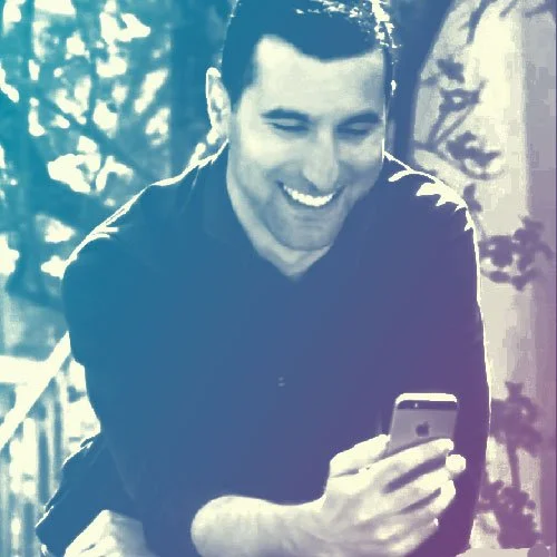 A smiling man looking at his phone outdoors Executive Insight HR