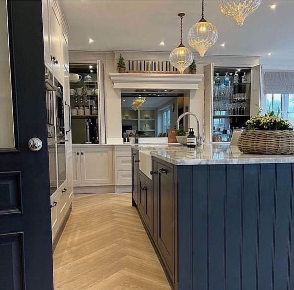 Modern kitchen with white cabinets, a blue island with a marble countertop, and glass pendant lights hanging from the ceiling.