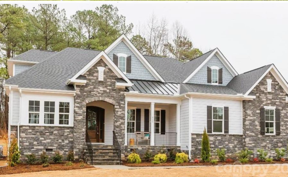 Front view of a modern two-story house with brick and white siding, multiple gabled roofs, and a small front porch with steps.