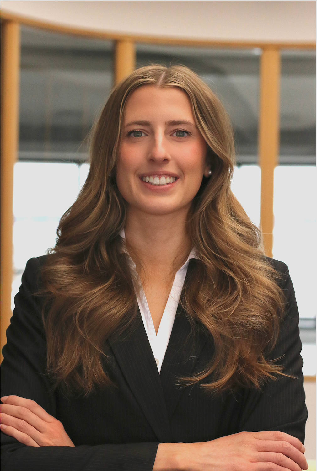 A professional woman with long, wavy brown hair, wearing a black blazer and white blouse, smiling with arms crossed in an office setting. Sealed Diehl helps you fix your resume, optimize your LinkedIn, and actually land interviews.