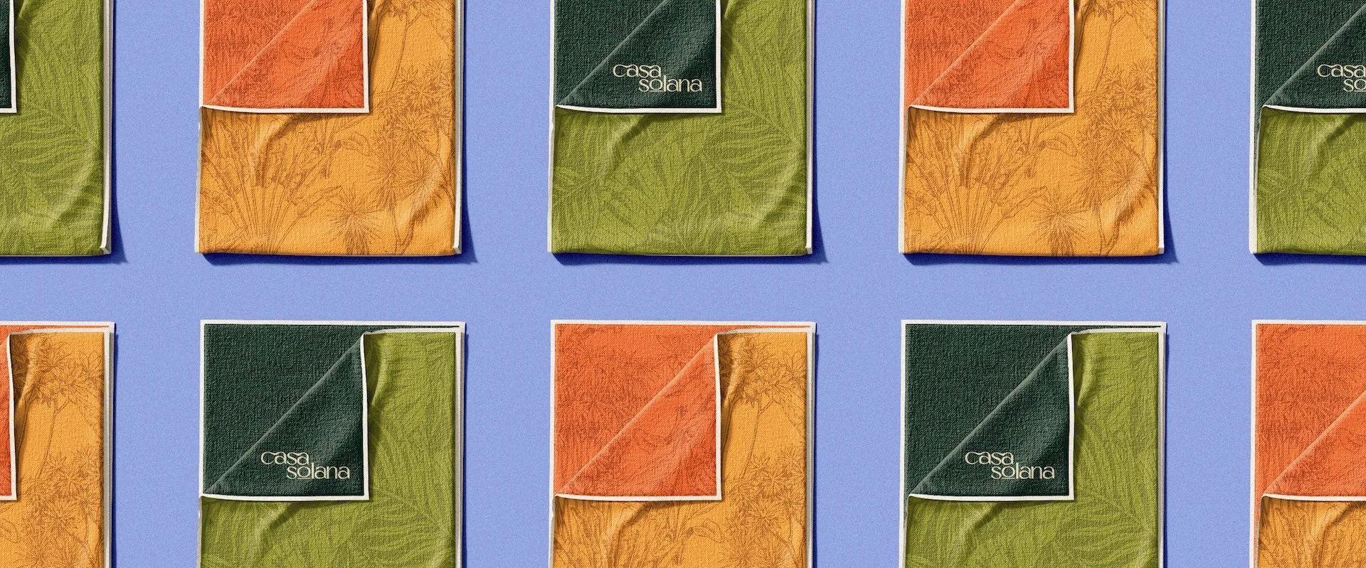 Multiple packs of Casa Solana towels in green, orange, and yellow colors arranged in a grid pattern on a blue background.