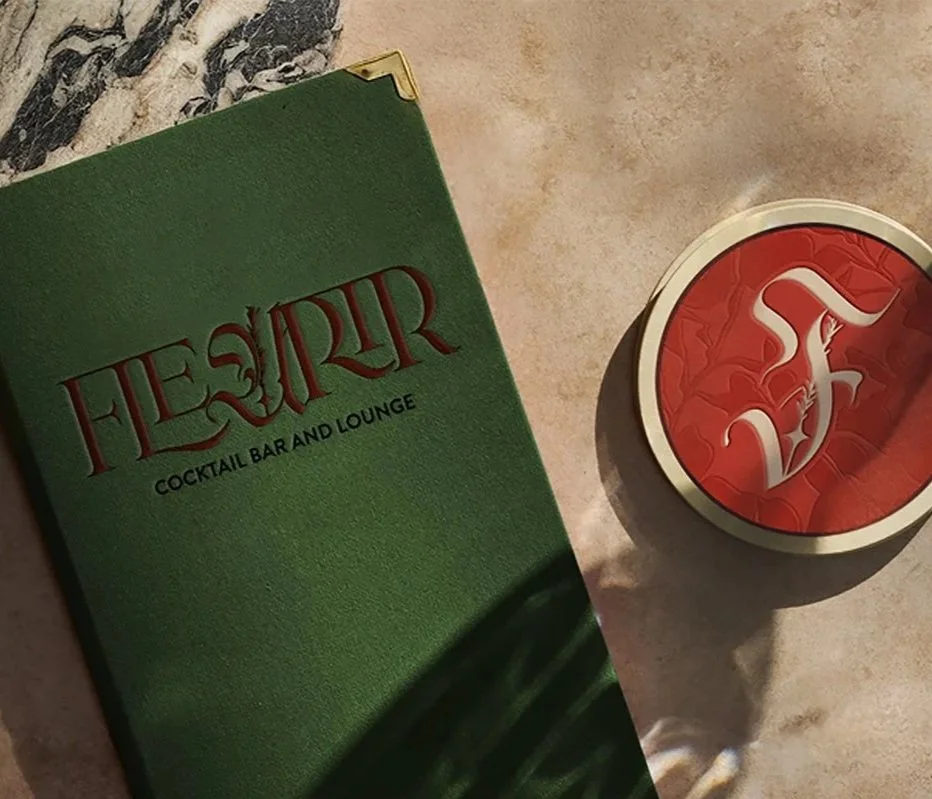 Green menu sheet with red text reading "Fleur Cocktail Bar and Lounge" next to a red coaster with a white stylized dragon.