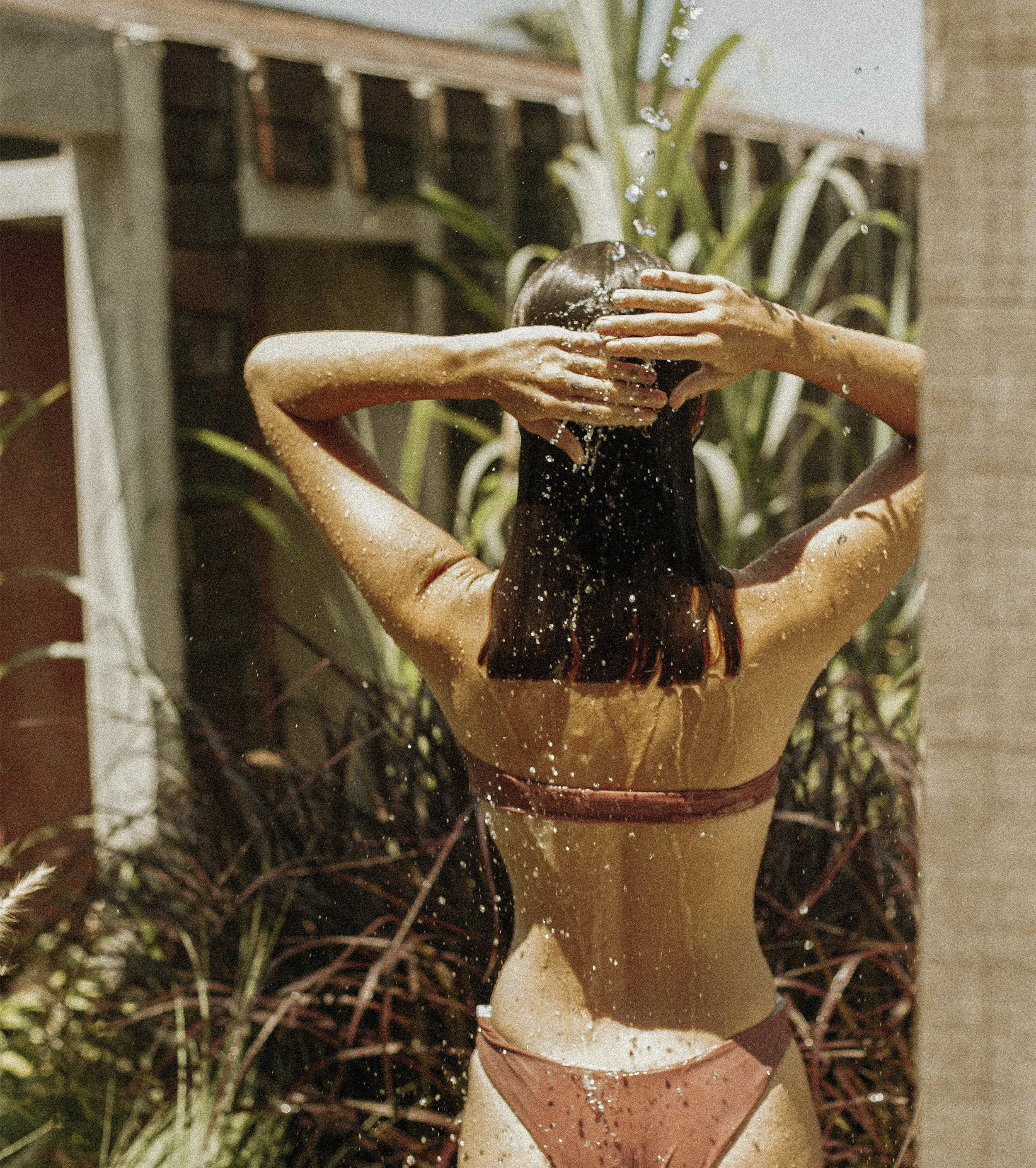 Woman washing her hair at an outdoor shower, outside of a Casa Solana guest room.