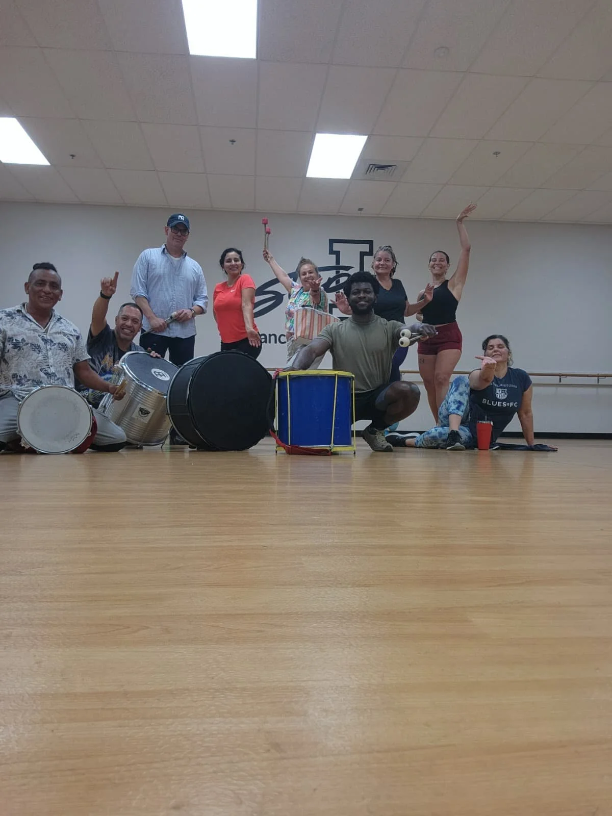 Group of nine people in a dance studio, posing with musical instruments and musical accessories. Samba class in sacramento
