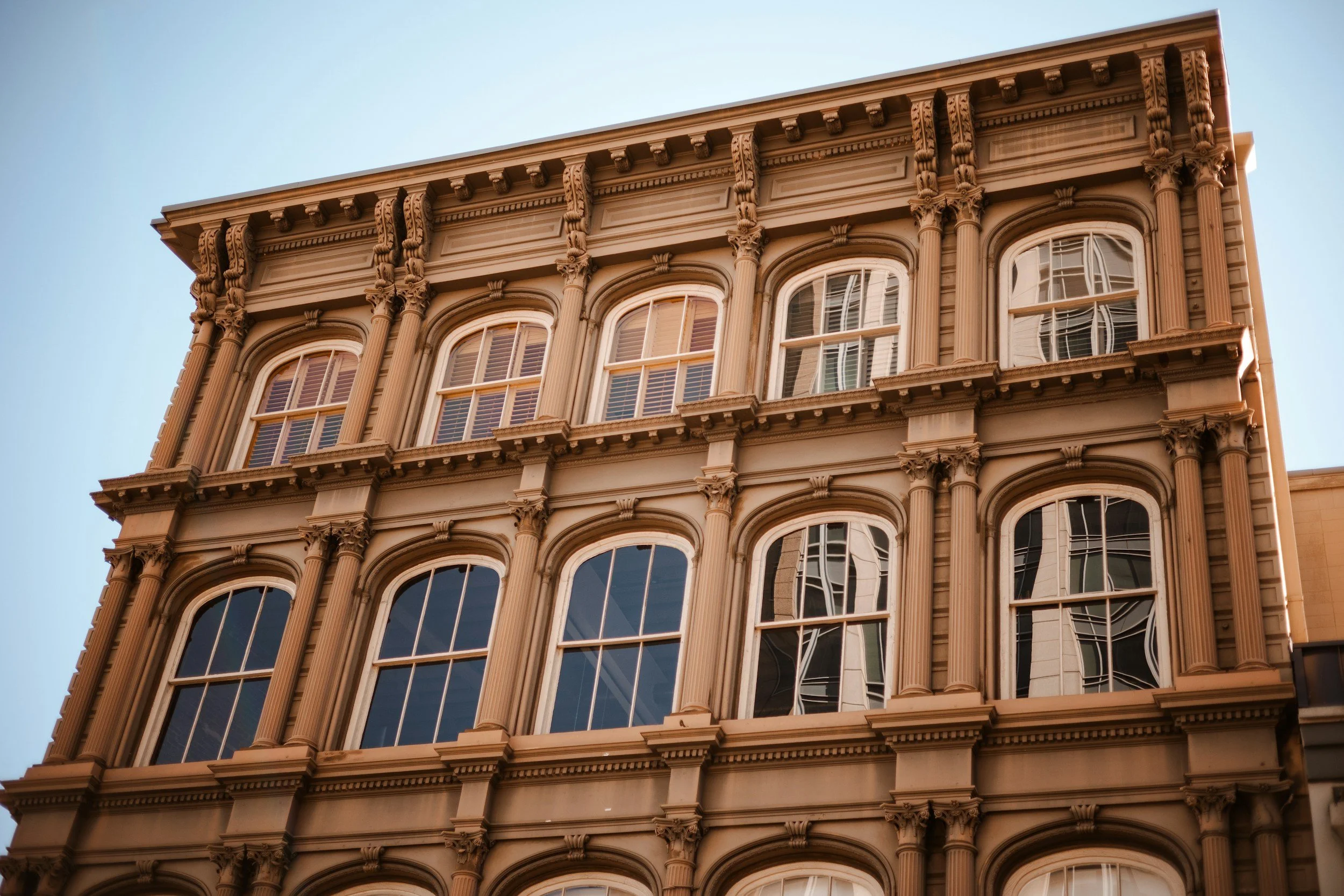 Upside-down view of a historic multi-story building with ornate architecture, large arched windows, and decorative columns.