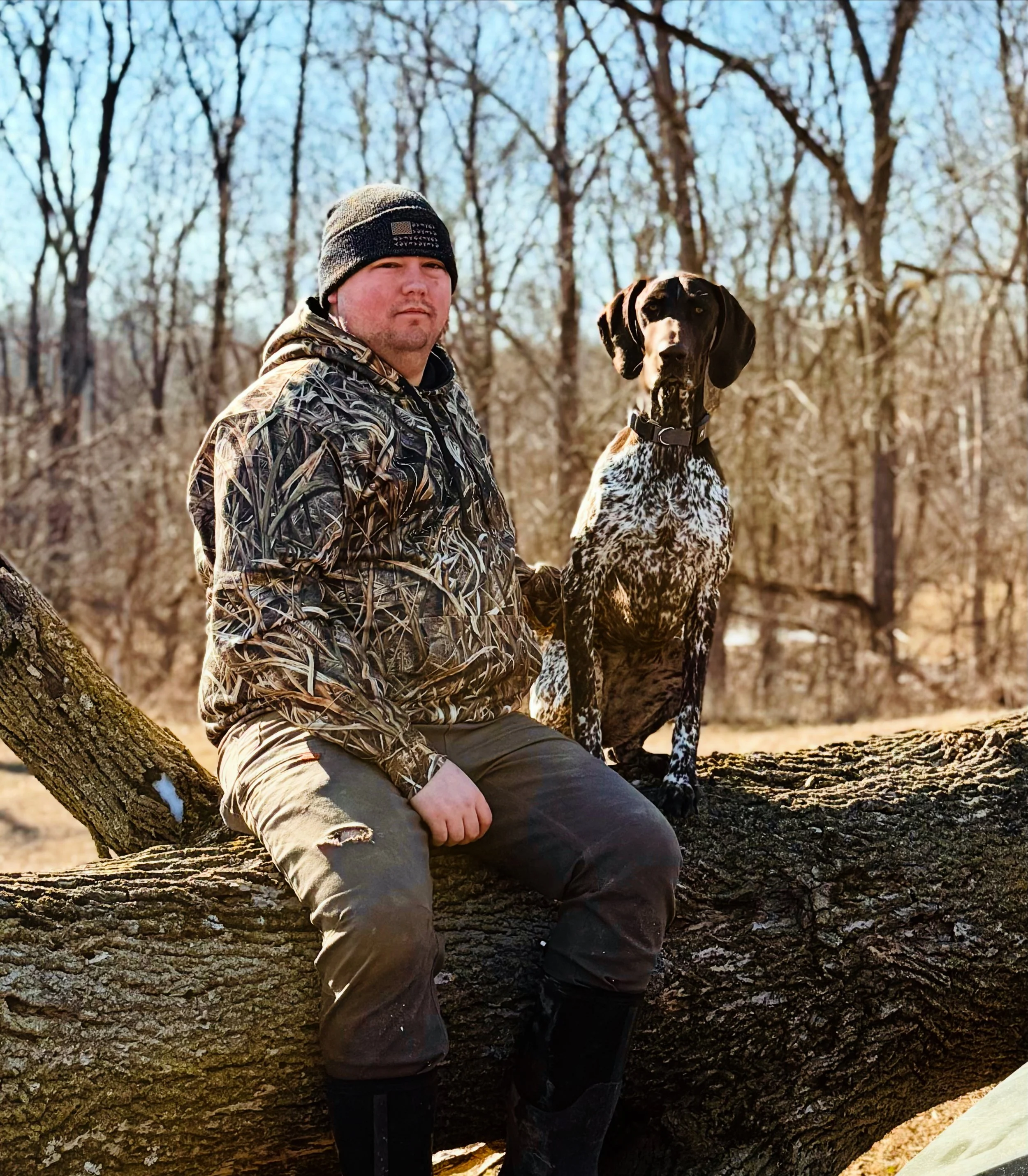 Codie Brewer sitting outdoors with the family dog on their Indiana homestead, representing the backbone of Brewer Family Farmstand.
