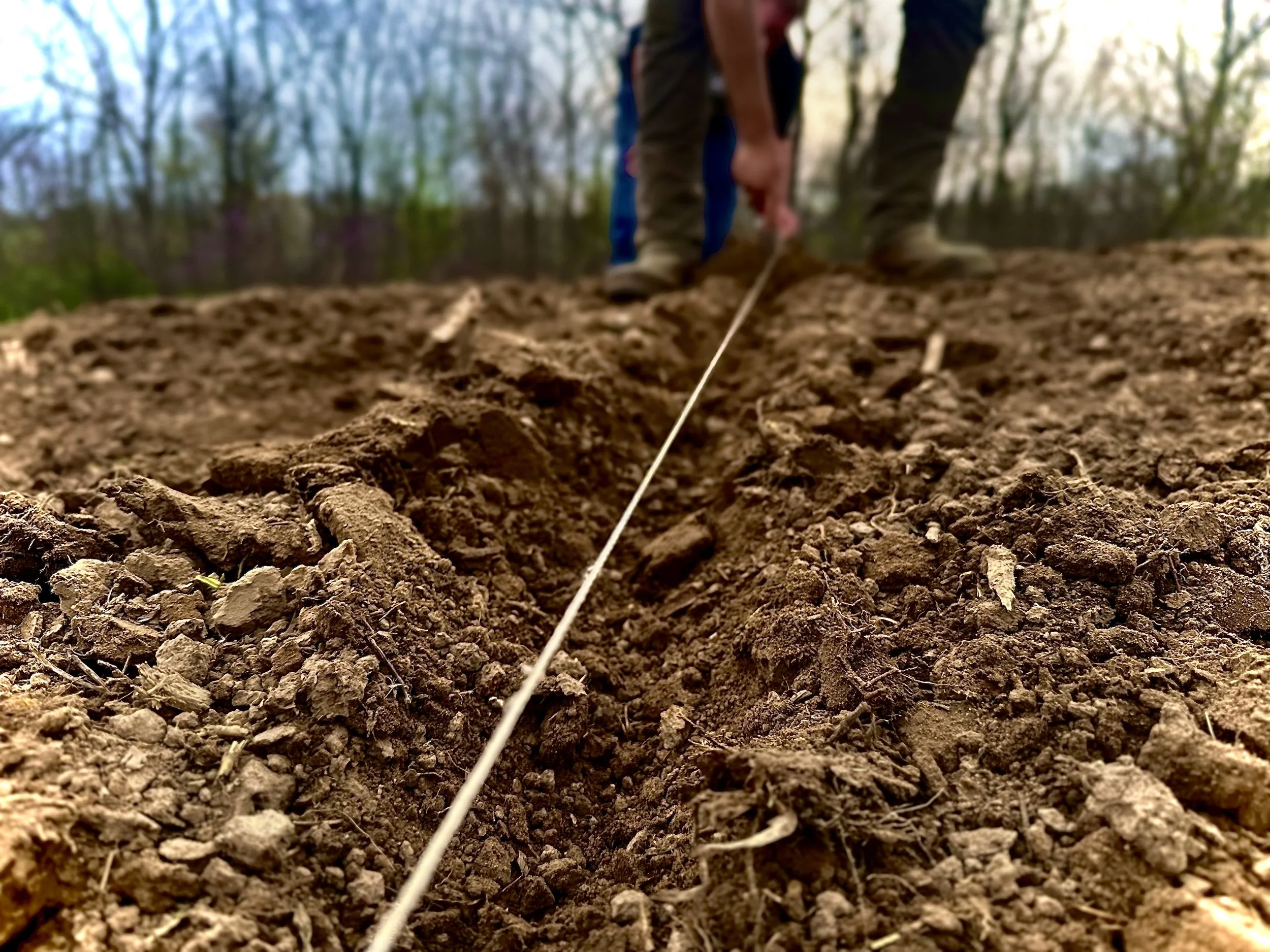 Hands measuring and preparing garden soil on the Brewer family homestead, symbolizing intentional, purpose-driven work.