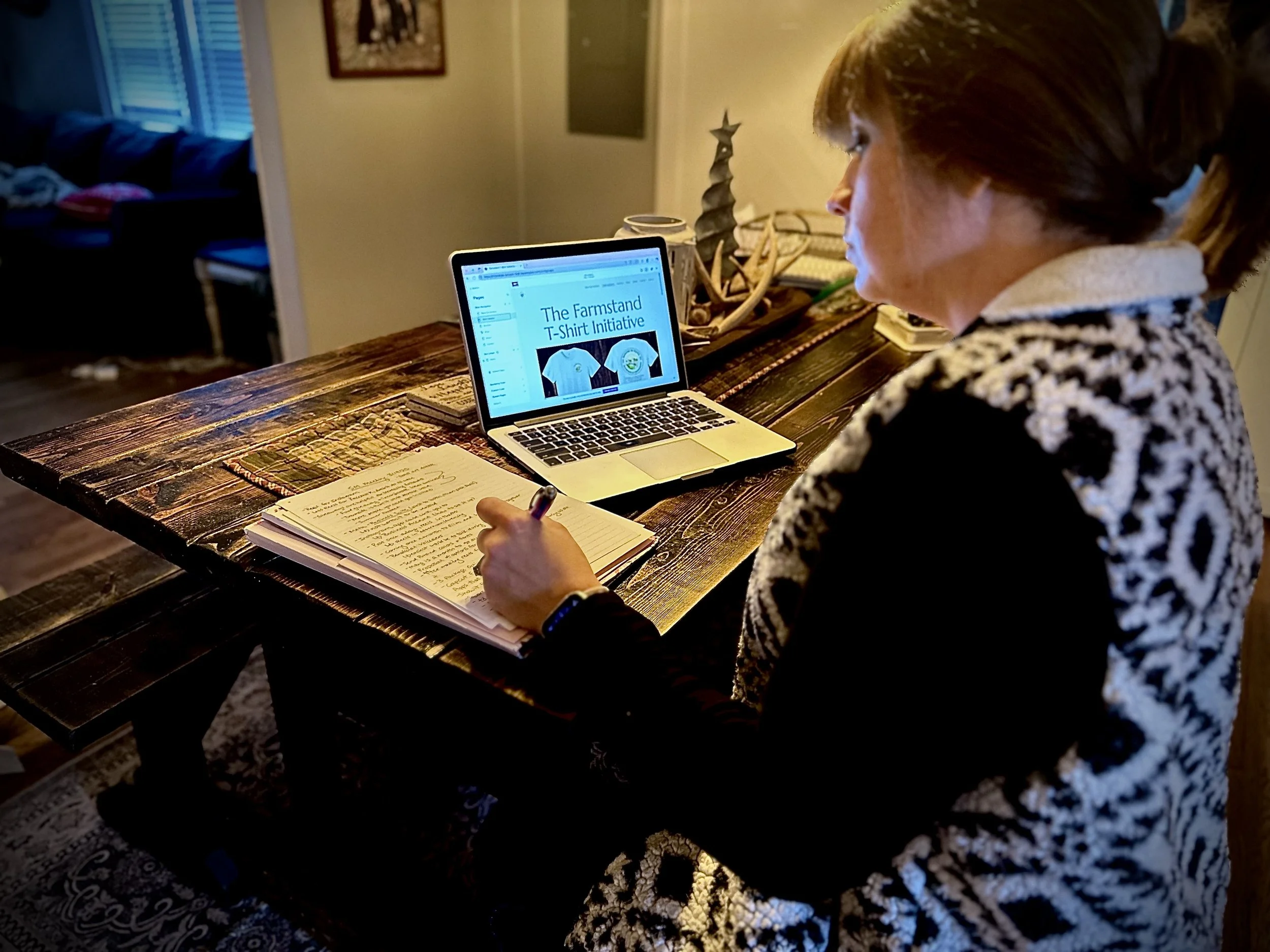 Linley Brewer working on digital content and website planning at her farmhouse table, developing online strategy for her small business.