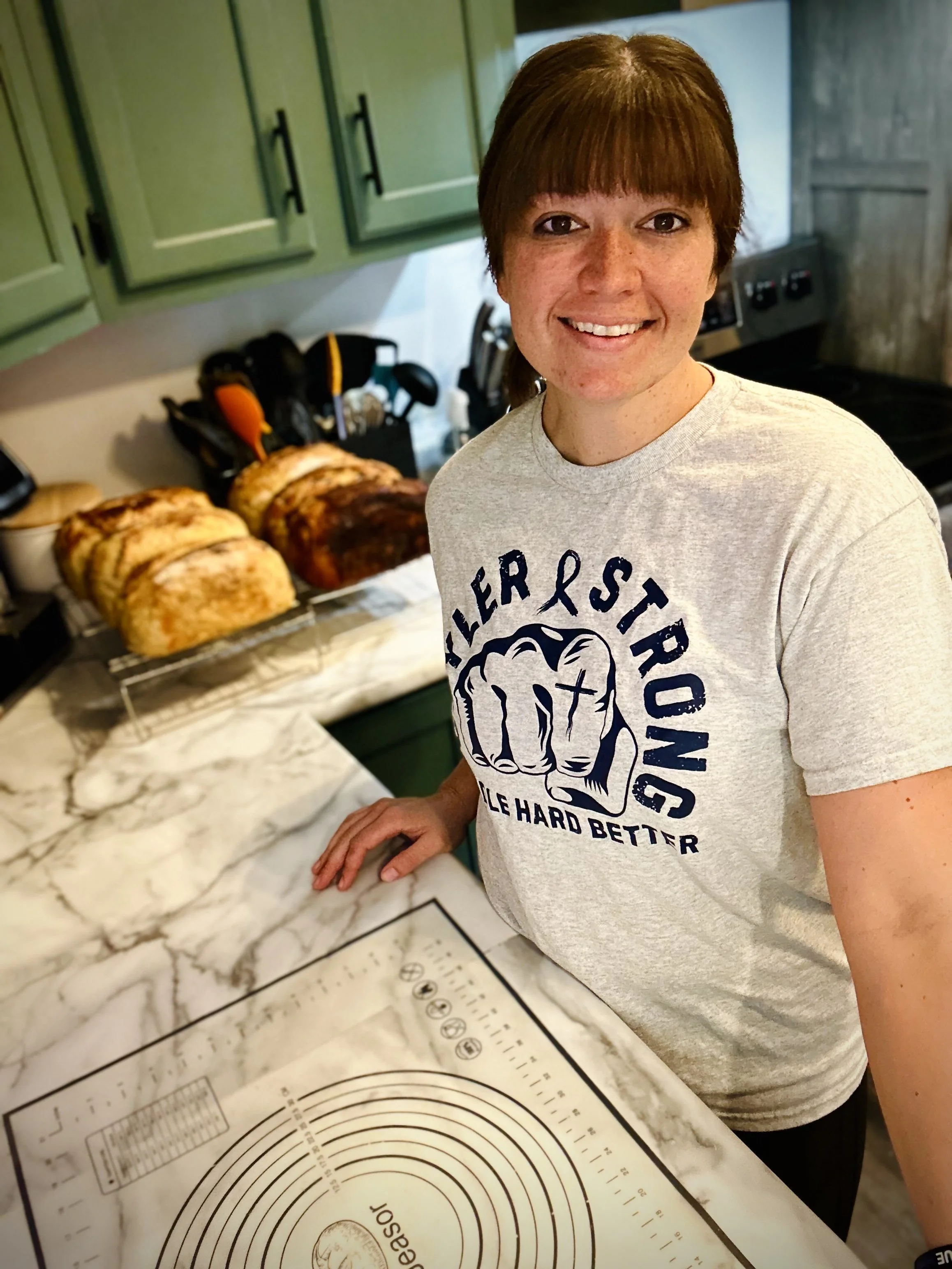 Linley Brewer, founder of Brewer Family Farmstand, smiling in the kitchen with freshly baked sourdough loaves.