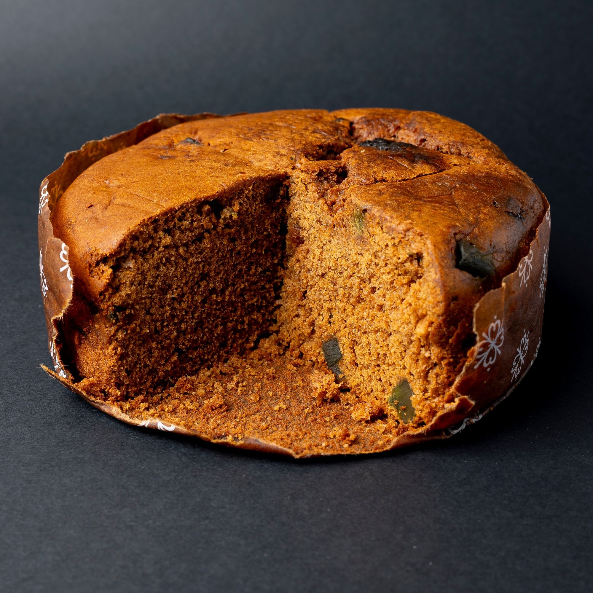A sliced Chilean Pan de Pascua, a dense spiced holiday cake-style bread with dried fruits and nuts, shown on a dark background.
