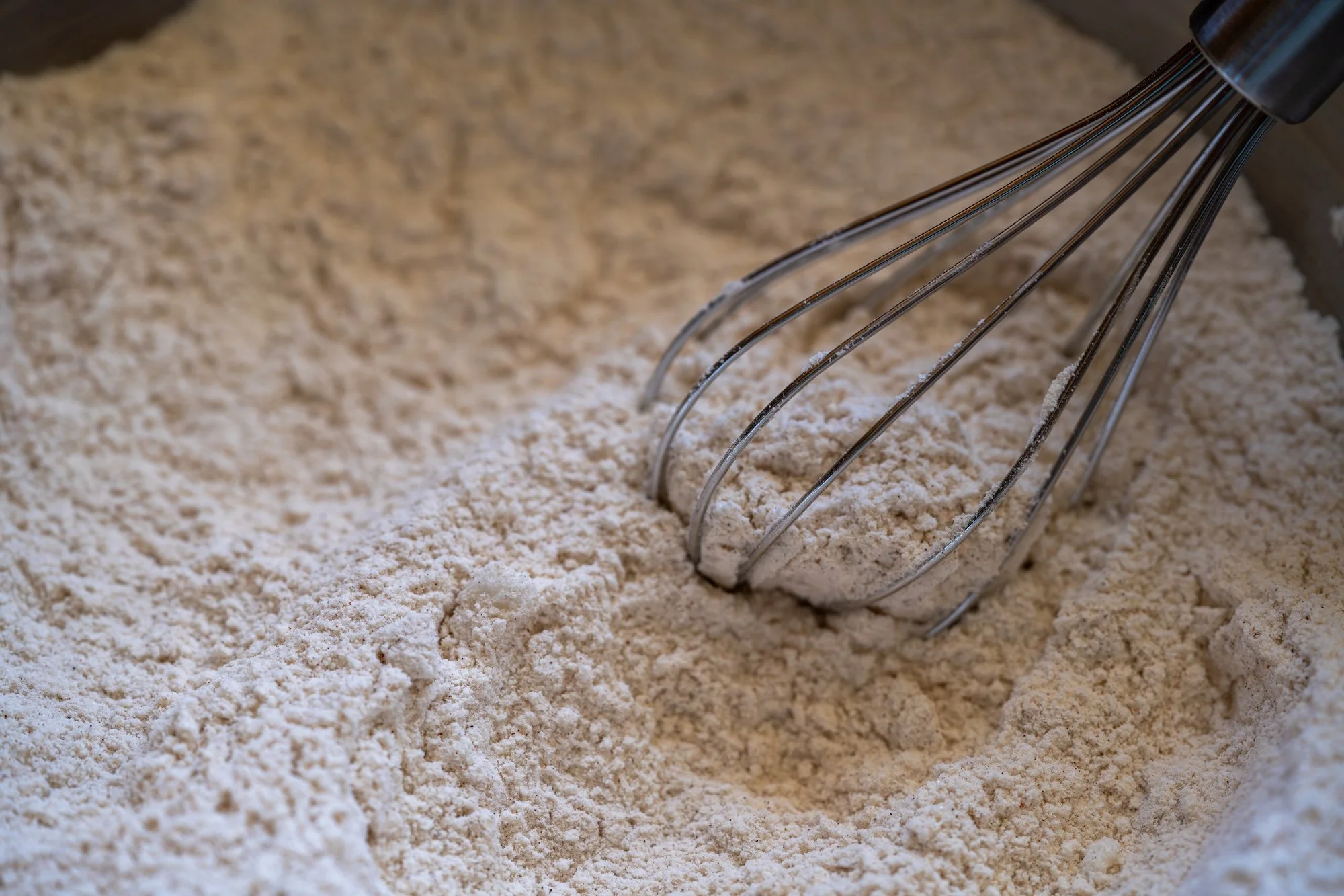 Dry ingredients for apple muffins being whisked together in a bowl, creating a light, even flour mixture.