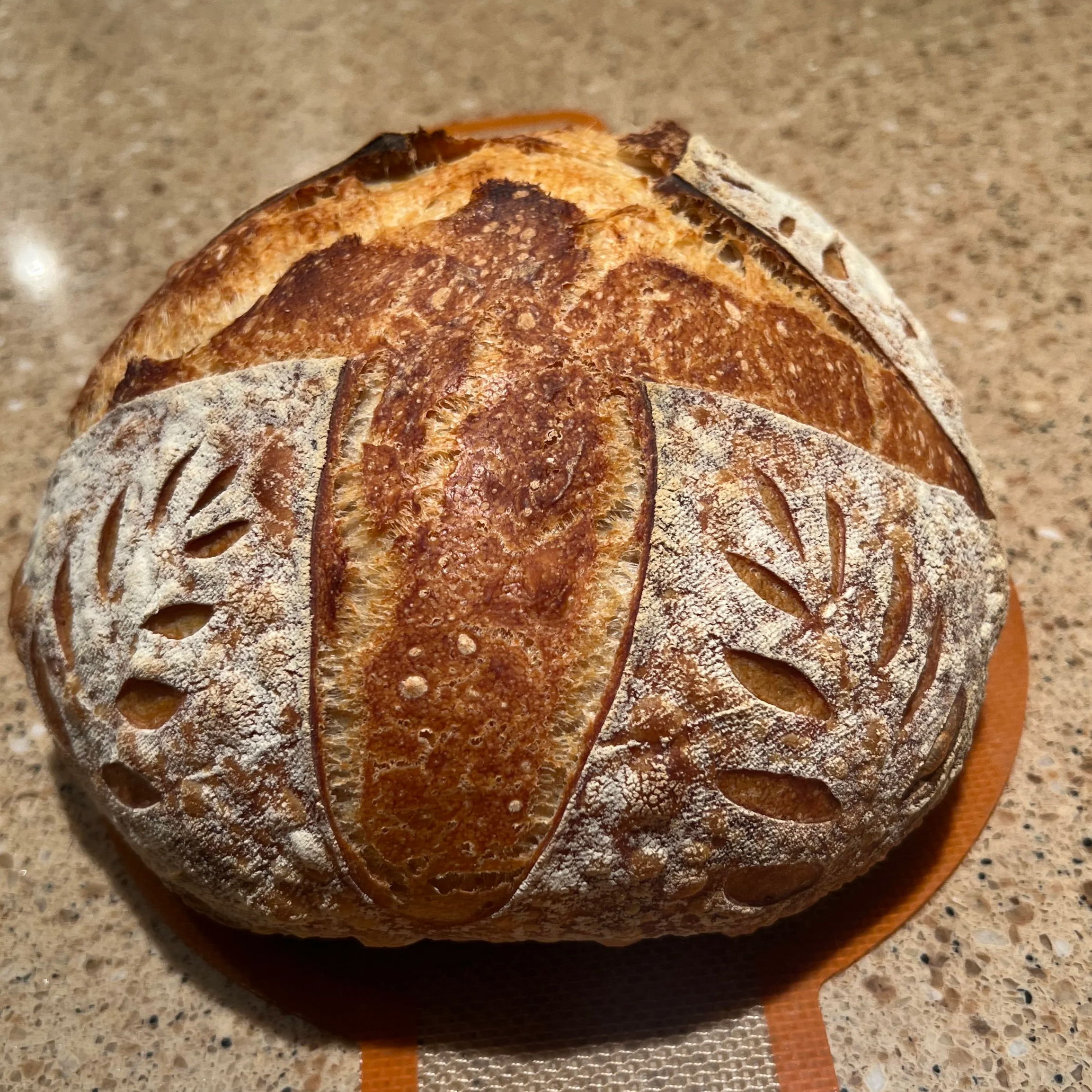 Freshly baked sourdough bread loaf with decorative scoring.