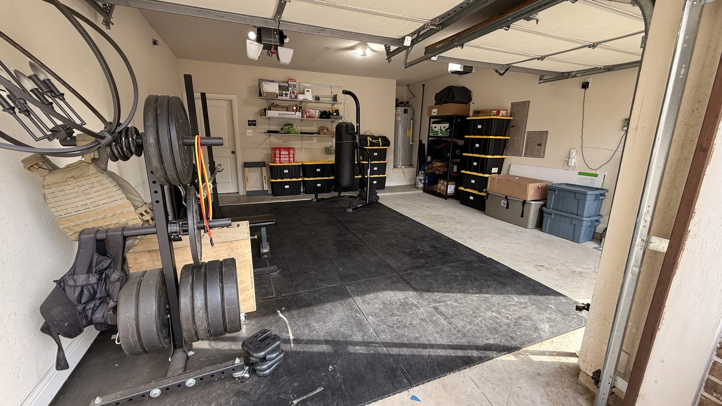 A garage with gym equipment, storage shelves, plastic bins, and boxes.