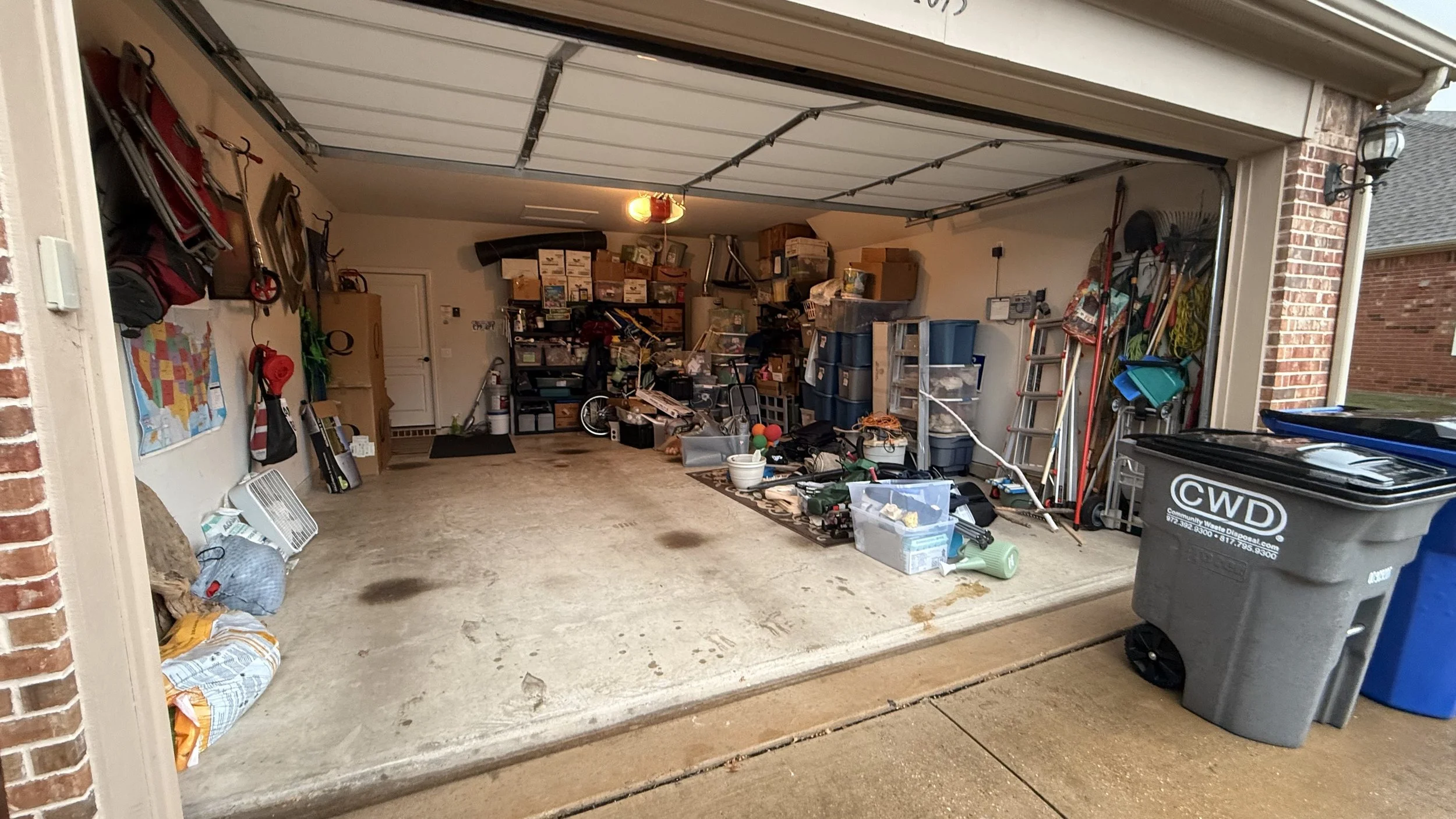 Open garage with storage shelves and various household items, tools, and sports equipment inside.