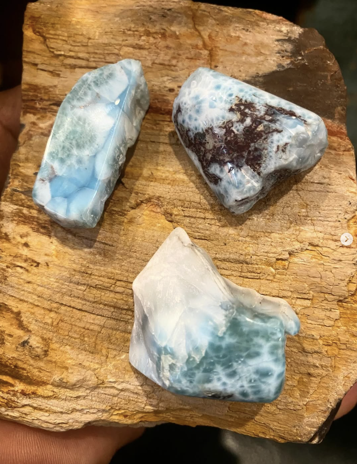 Three large polished stones with blue and white and brown coloration on a rough wooden surface.