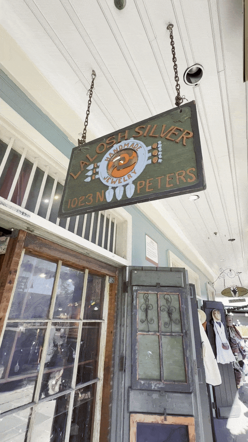 Sign for Laosh Silver Jewelry store hanging from ceiling inside shopping mall.