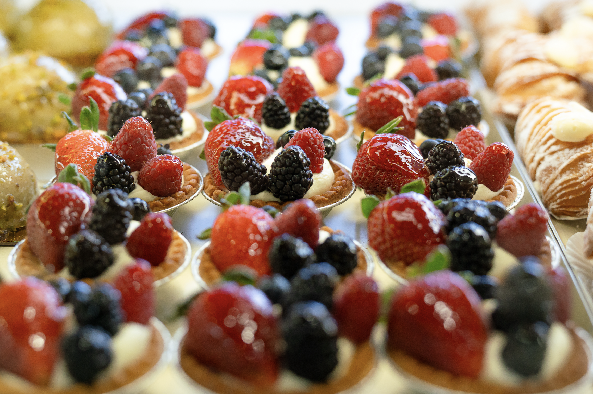 Assorted mini desserts topped with fresh strawberries, blackberries, and raspberries.