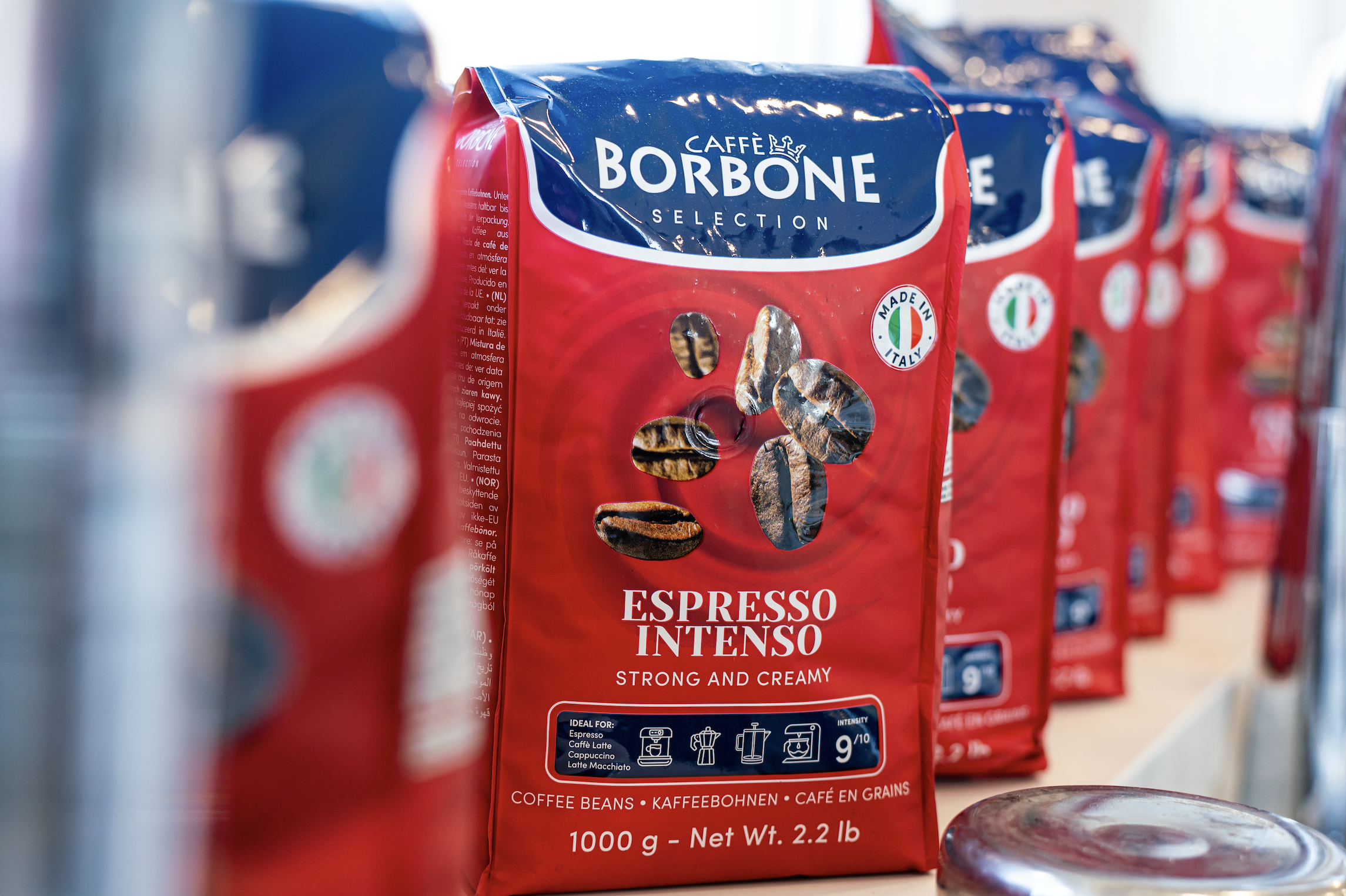 Red and blue packages of Caffè Borbone Espresso Intenso coffee beans displayed on a shelf.