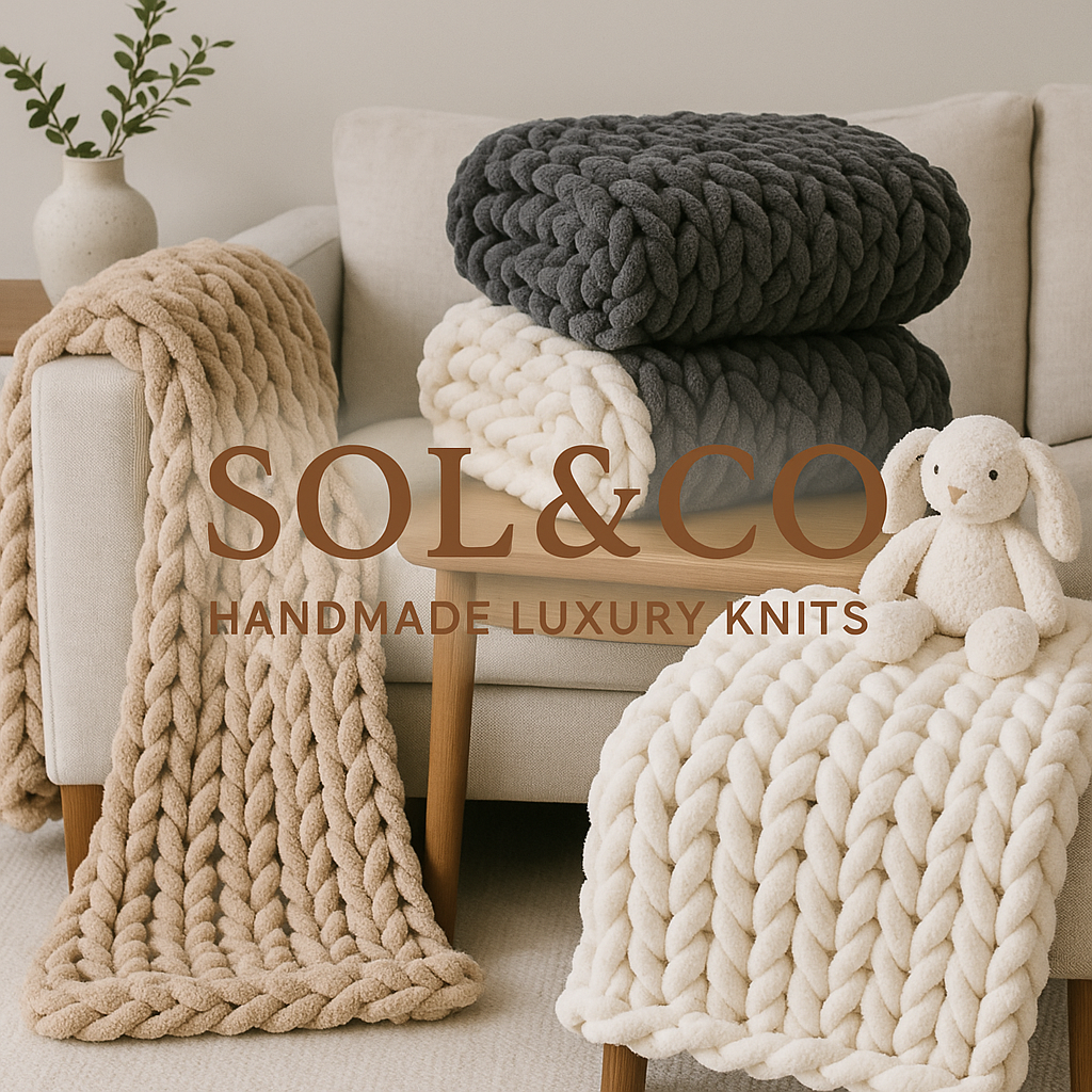 Stacked oversized chunky knit blankets in black, cream, and beige colors, with a plush teddy bear on a beige blanket, on a mid-century modern sofa in a cozy living room setting.