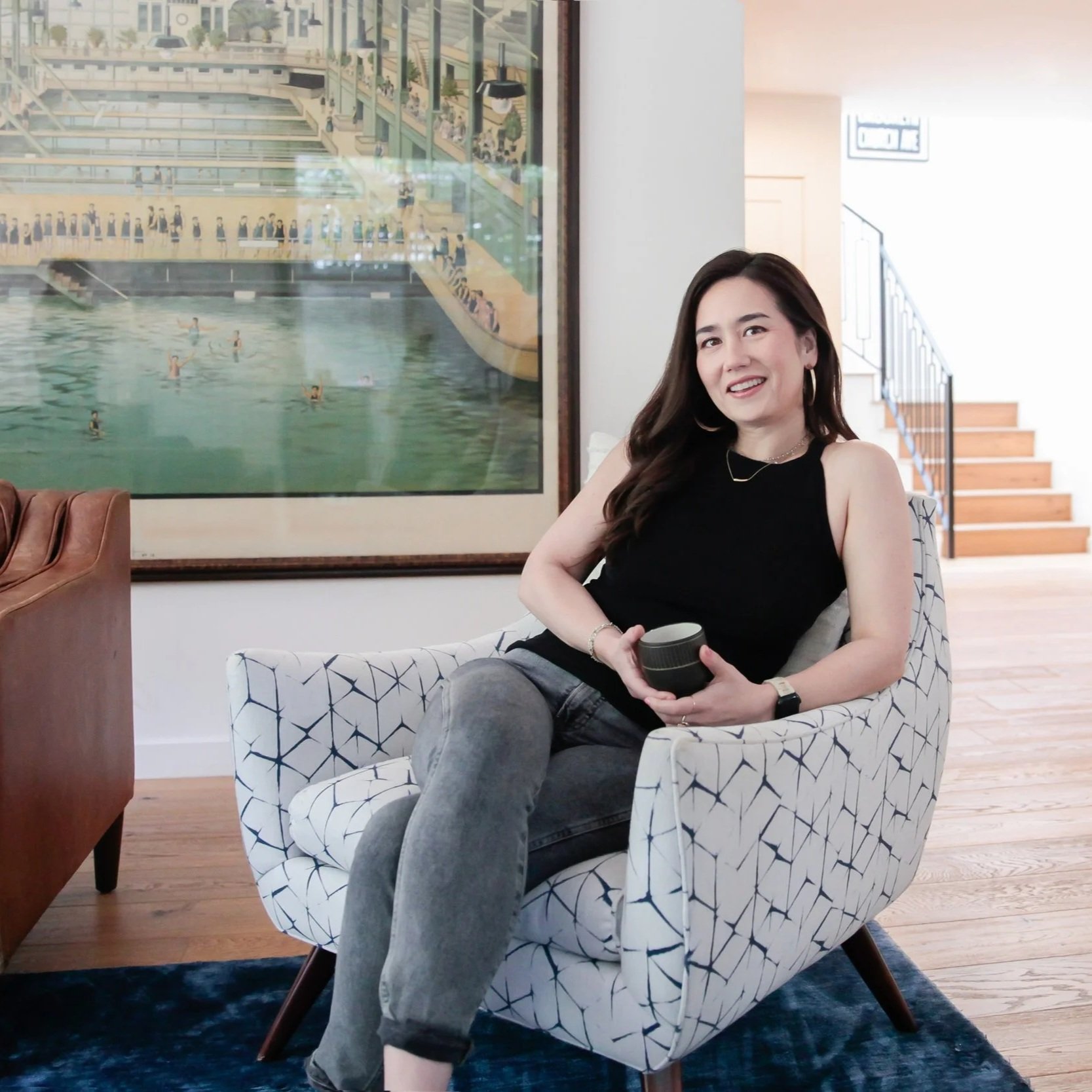 Portrait of The Warm Edit founder seated in a living space with artwork in the background.