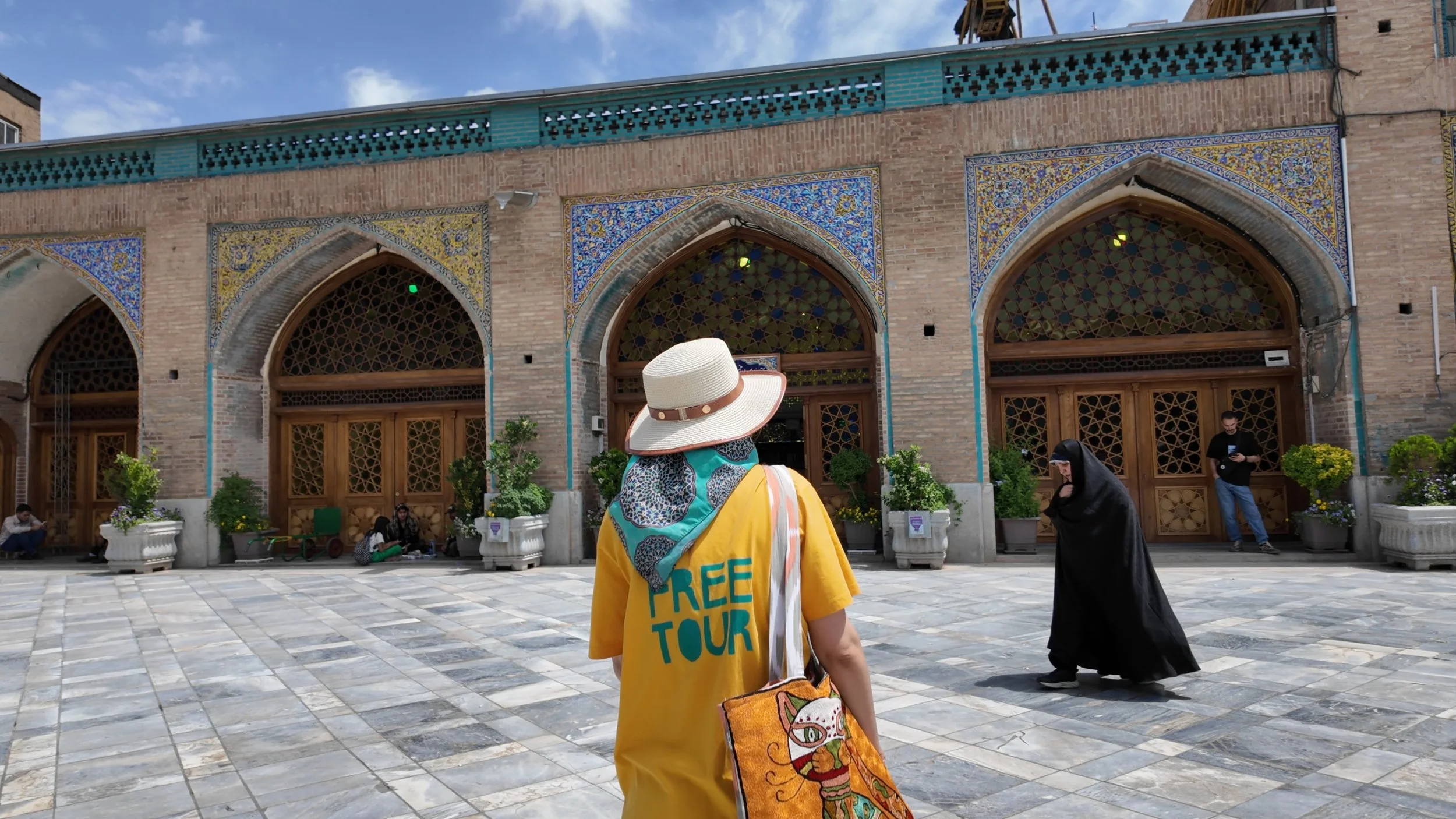 Feya, my tour guide in Tehran, dressed in modern style, contrasting with a woman in a traditional black chador.