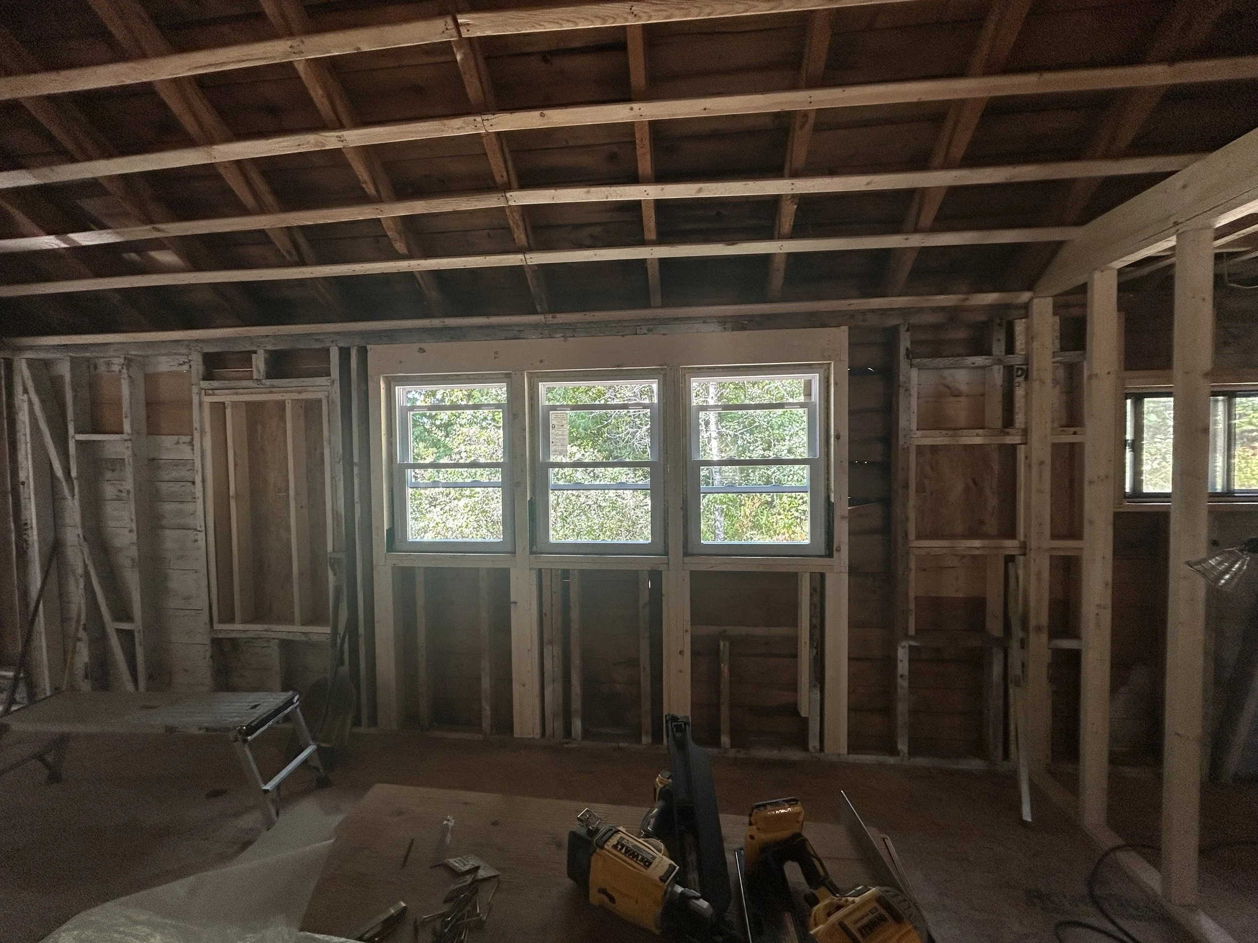 Interior of a house under construction with exposed wooden framing, windows, and construction tools on a table. General contractor. Carpentry.