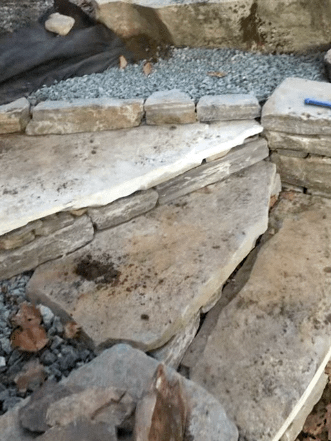 Stack of large, flat stones and gravel at a construction or landscaping site.
