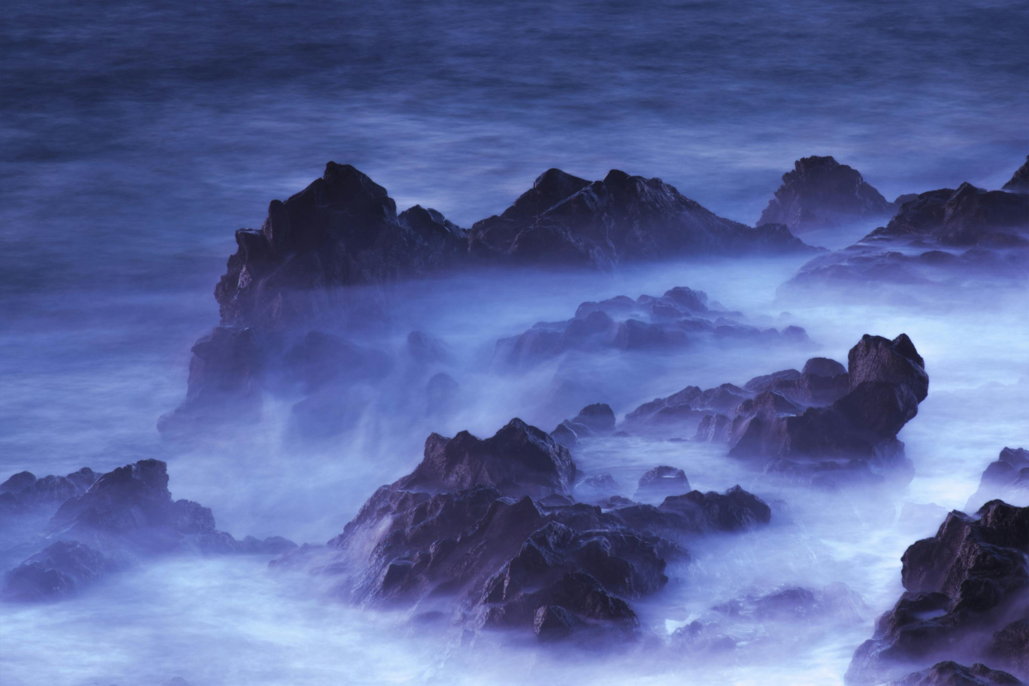 A moody coastline with waves crashing against a rocky shore under soft, atmospheric light, representing the strength and steadiness of the shore during a storm.