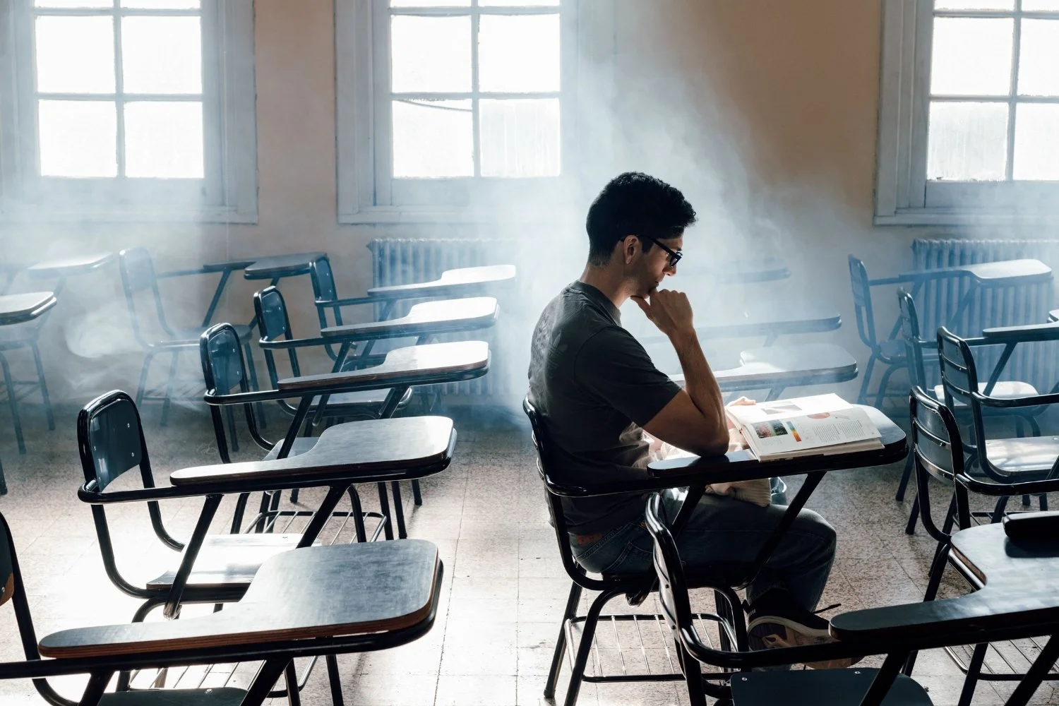 An educator or student pausing at a quiet workspace to take a grounding breath, representing healthy work-life boundaries and mindfulness.