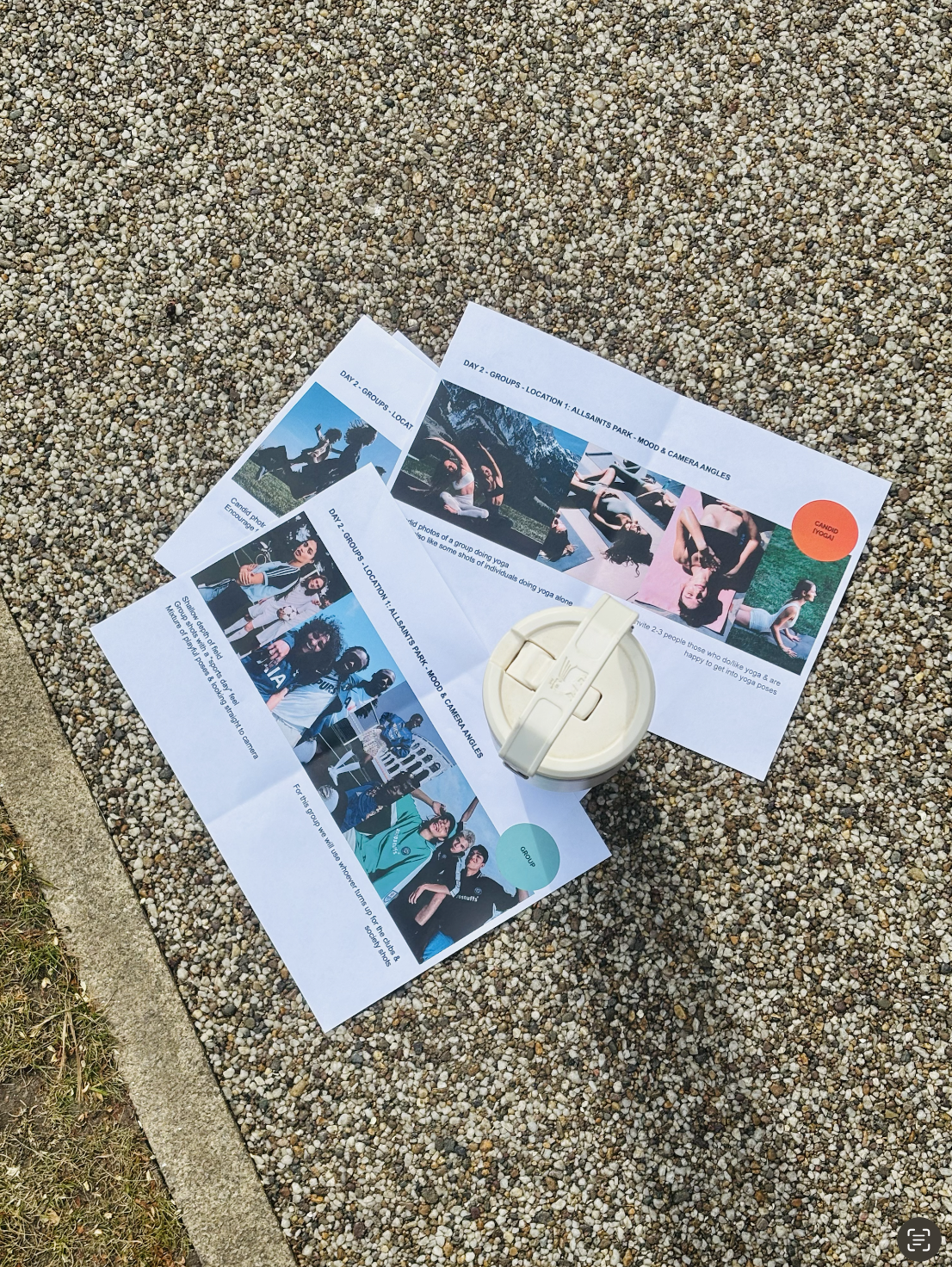 Printed sheets with group photos, text, and colorful circles, a stainless steel reusable bottle, placed on a gravel surface.