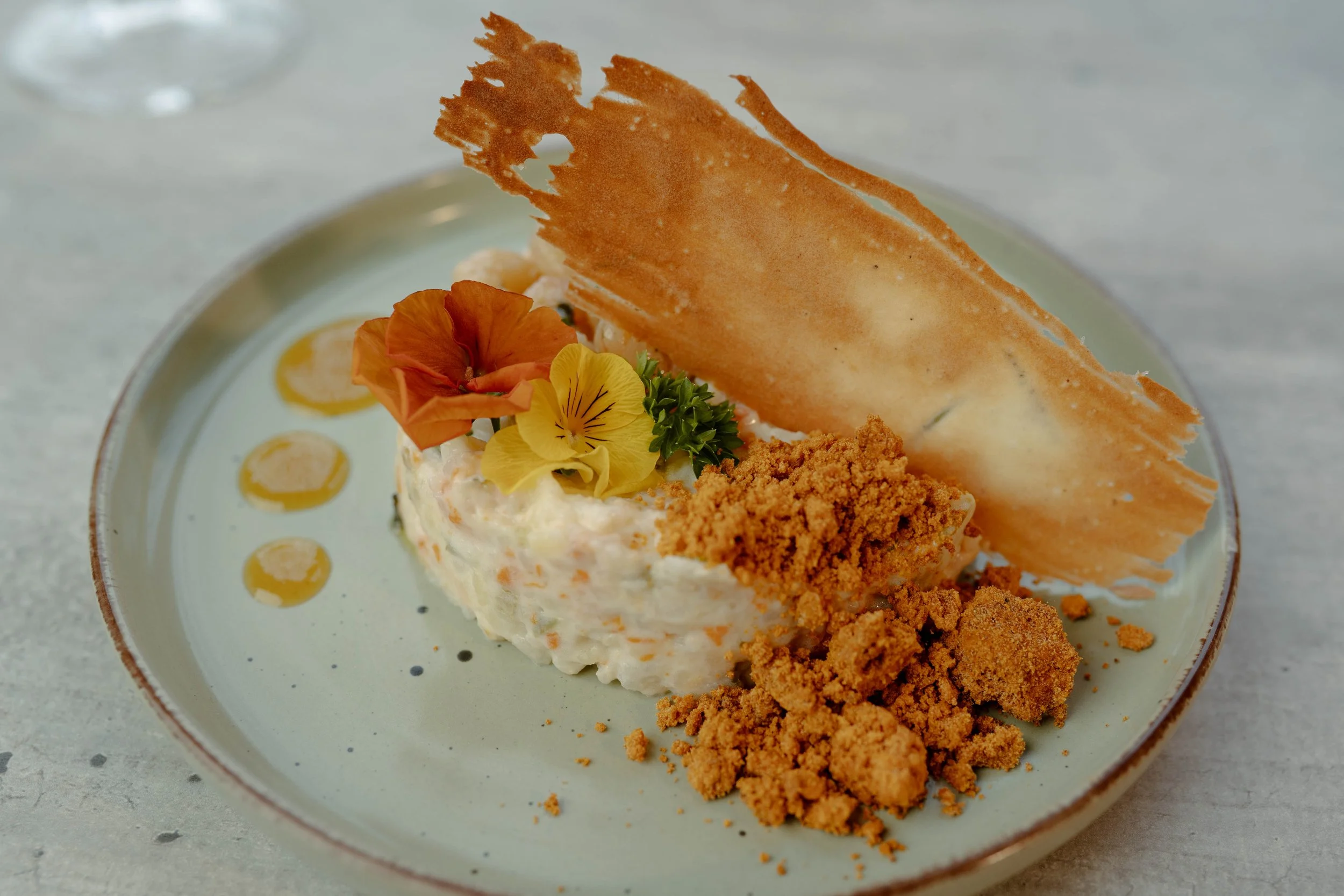 Plato de Ensaladilla de gambas al ajillo con toques de naranja amarga emplatado.