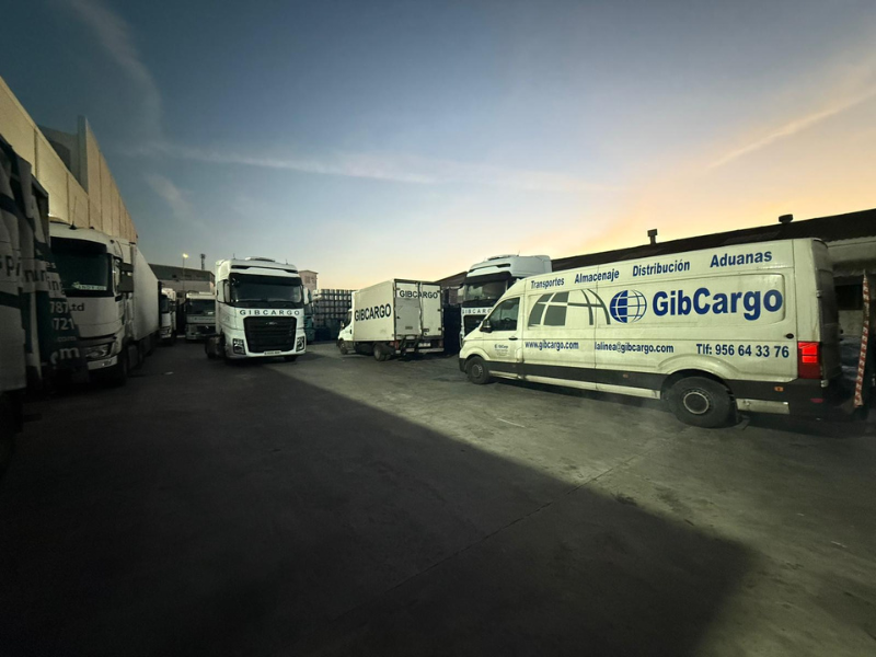 Fleet of cargo trucks and delivery vans parked at a logistics terminal during dusk.
