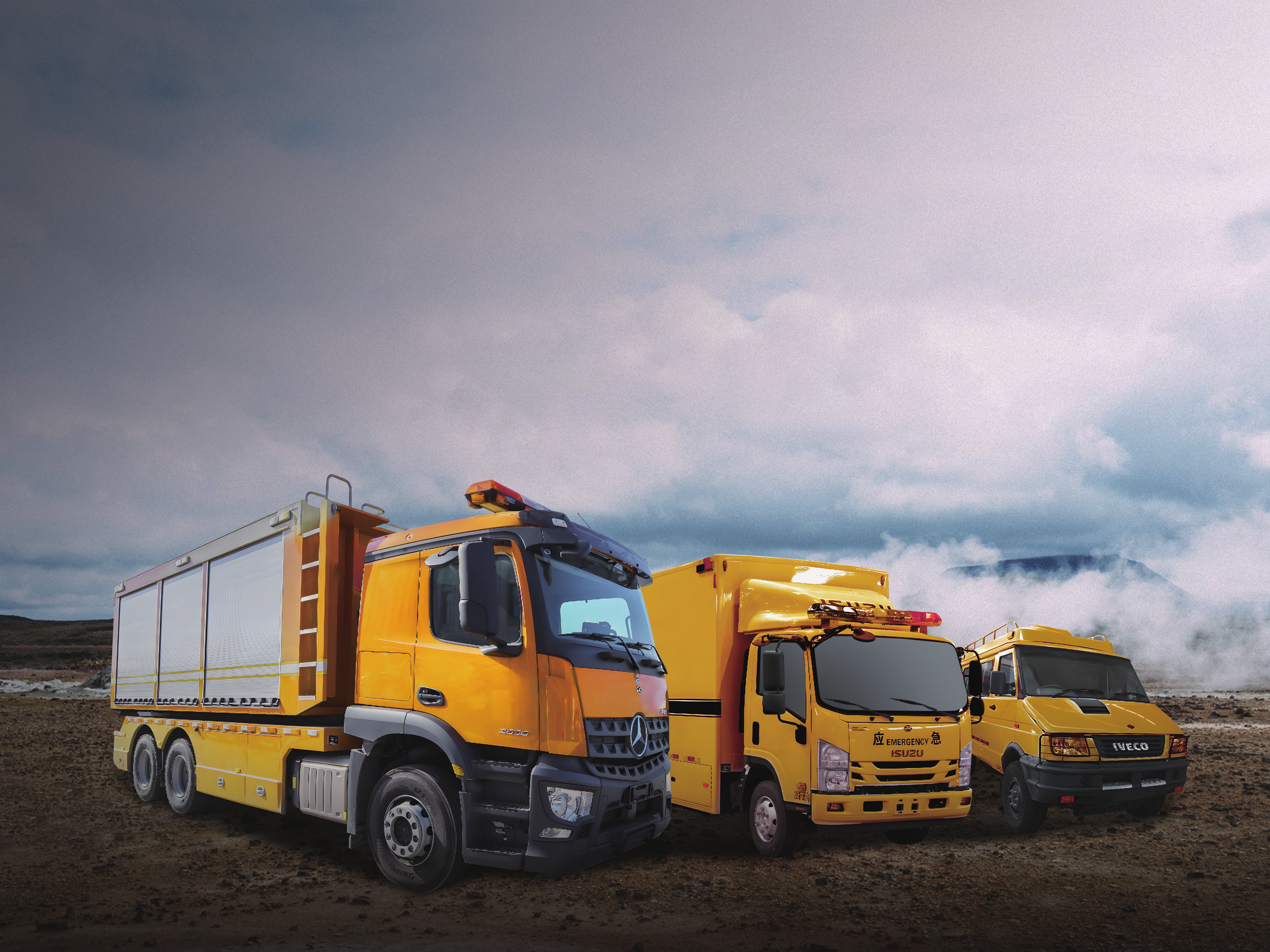 Three yellow emergency and utility vehicles parked on dirt ground with cloudy sky in background.