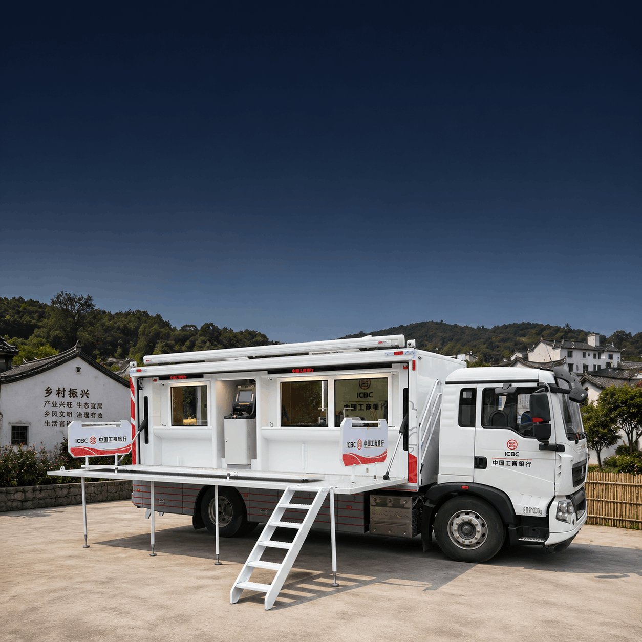 White mobile office truck with stairs and railing, branded with ICBC logos, parked outdoors with a backdrop of traditional Chinese buildings and green hills under a dark sky.