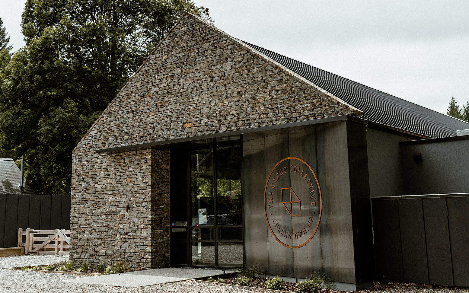 Exterior of a the Cargo Collective Brewhall, made of stone with a large glass entrance door.