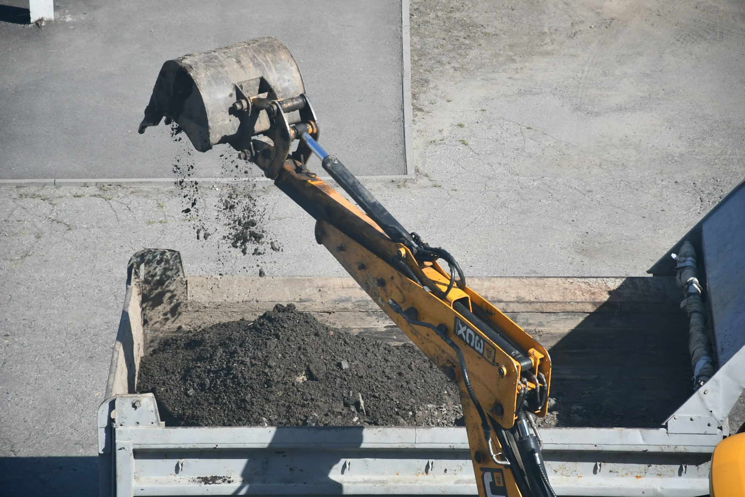 A yellow excavator loading dirt into a dump truck, representing heavy asset finance.