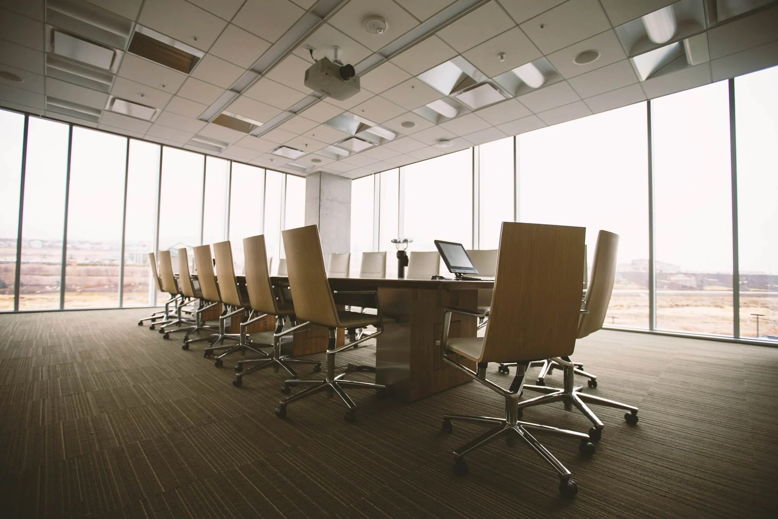 A modern corporate boardroom table with empty chairs overlooking a landscape, representing legal and settlement coordination.
