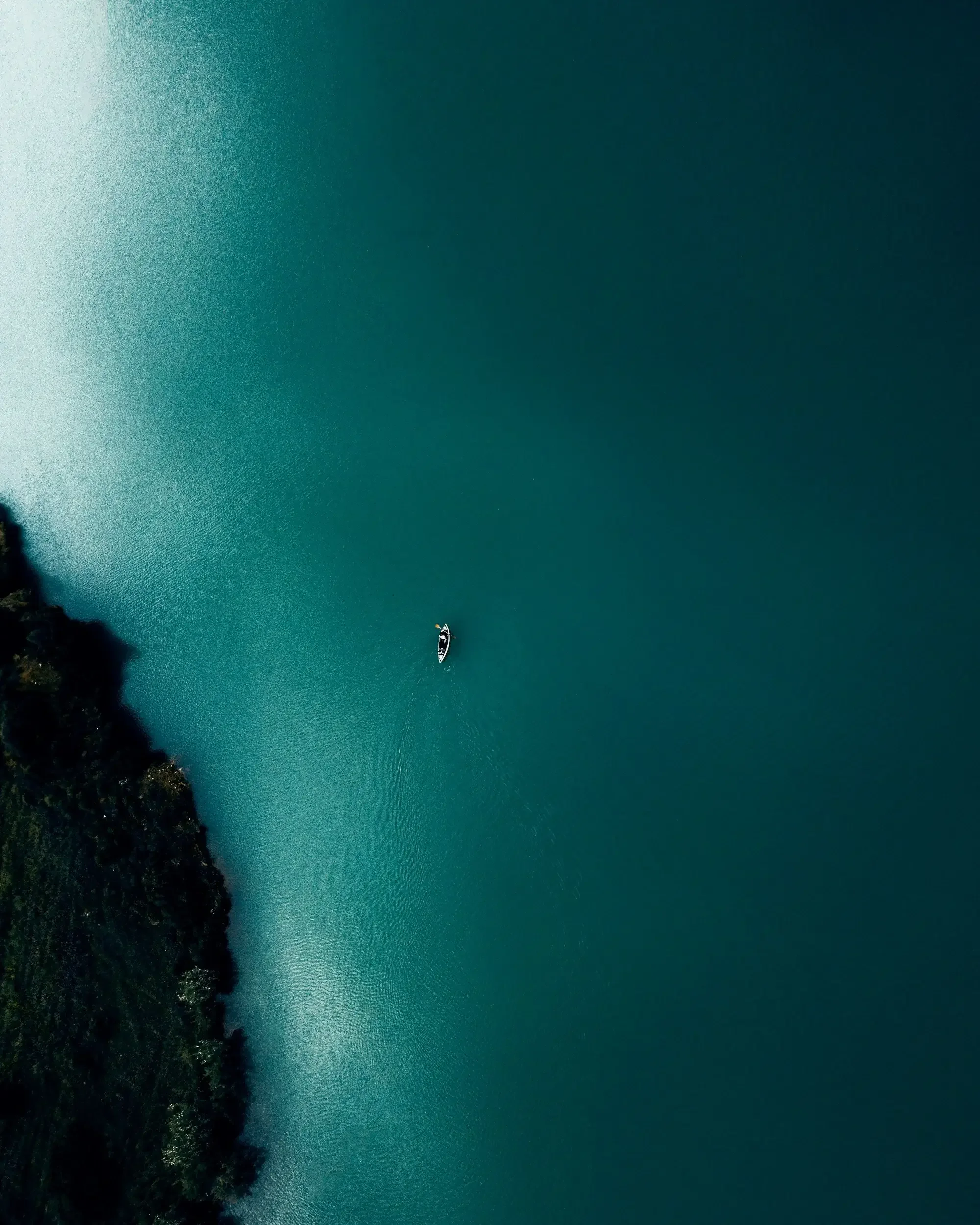 Aerial view of a kayak navigating calm green waters, representing strategic business direction