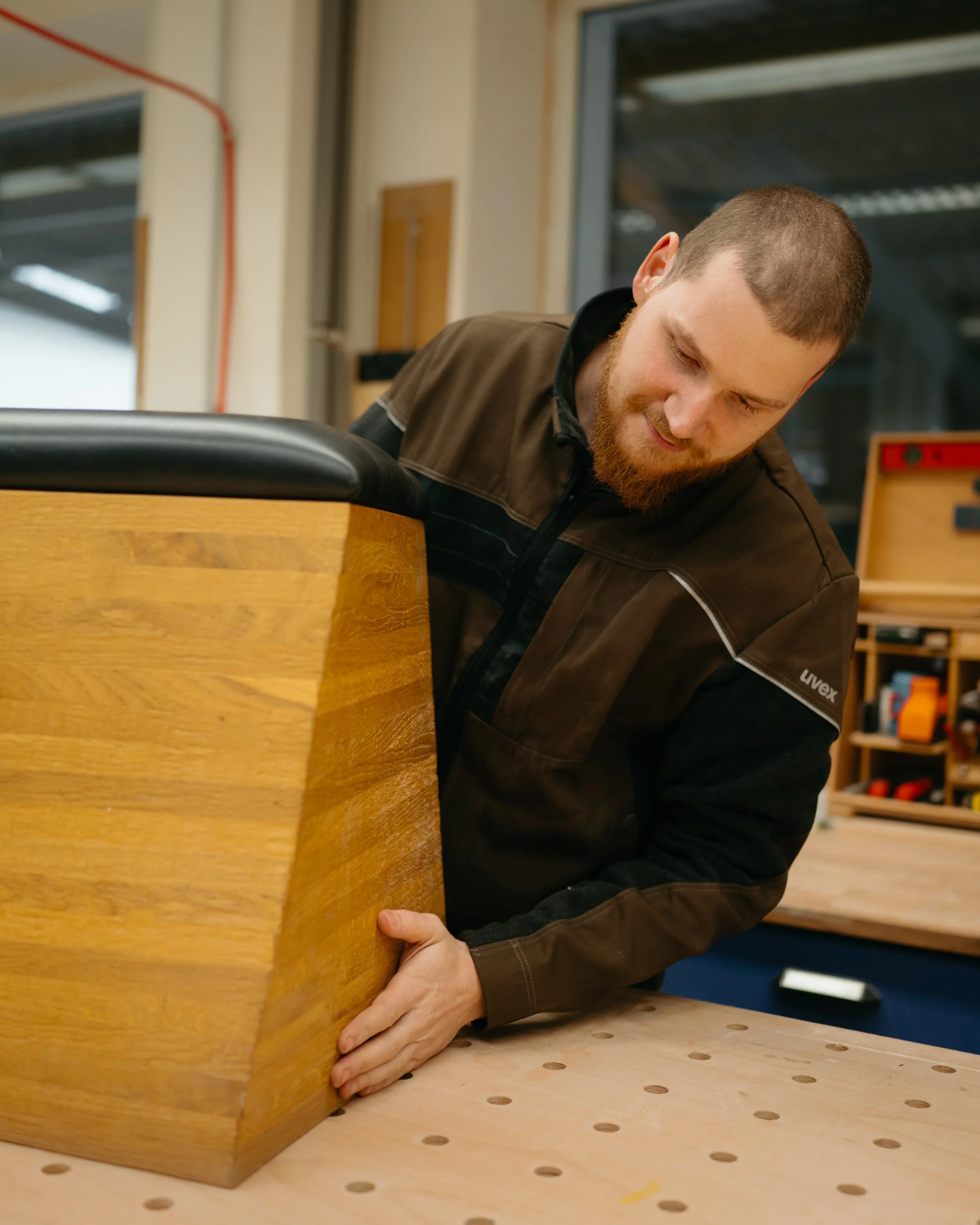 Mann beim Zusammenschrauben eines Holzstücks in einer Werkstatt.