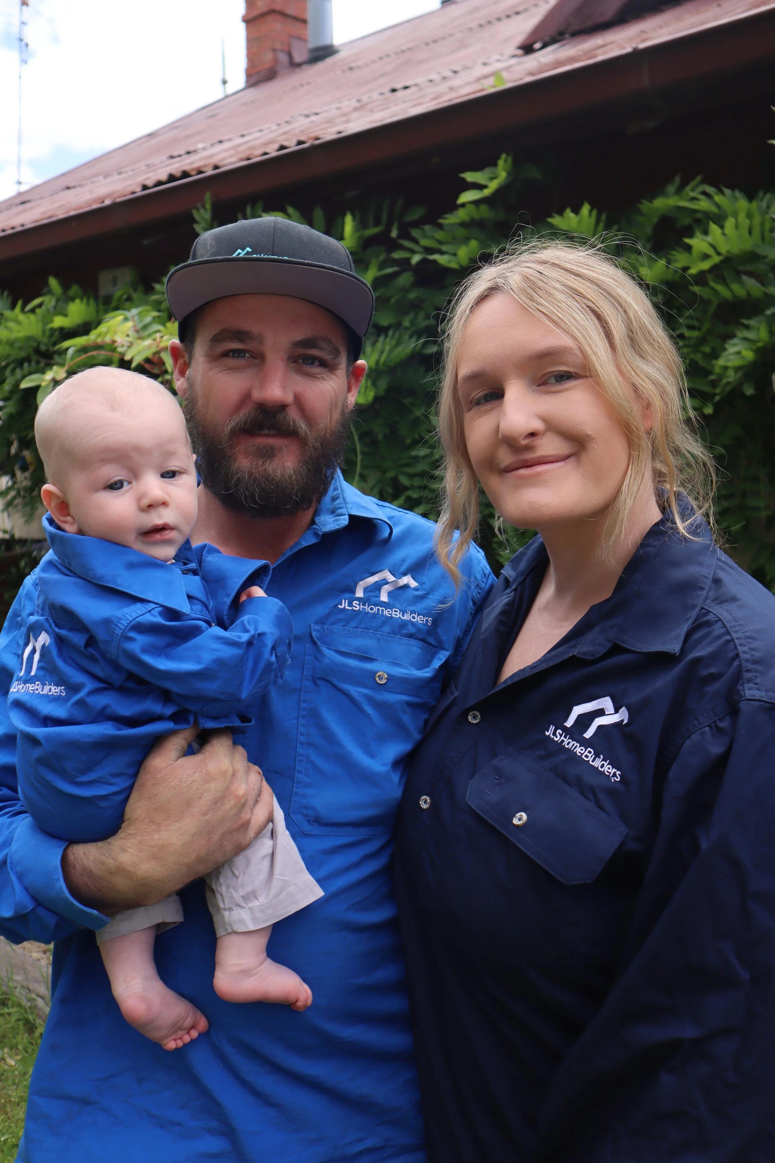Jack holding his Son smiling with partner Jenna. All wearing JLS home Builder shirts.