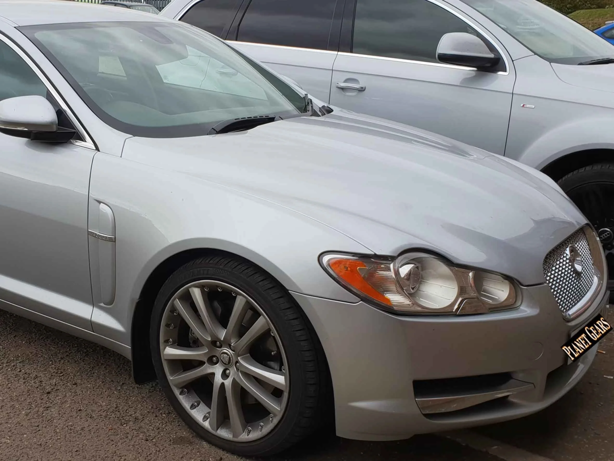 Silver sports car parked next to a gray SUV, showing the front and side view of the vehicle.