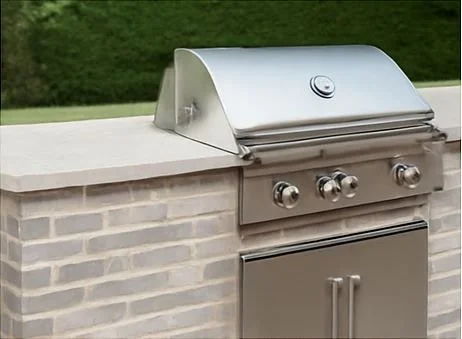 Outdoor stainless steel gas grill on a brick outdoor kitchen counter